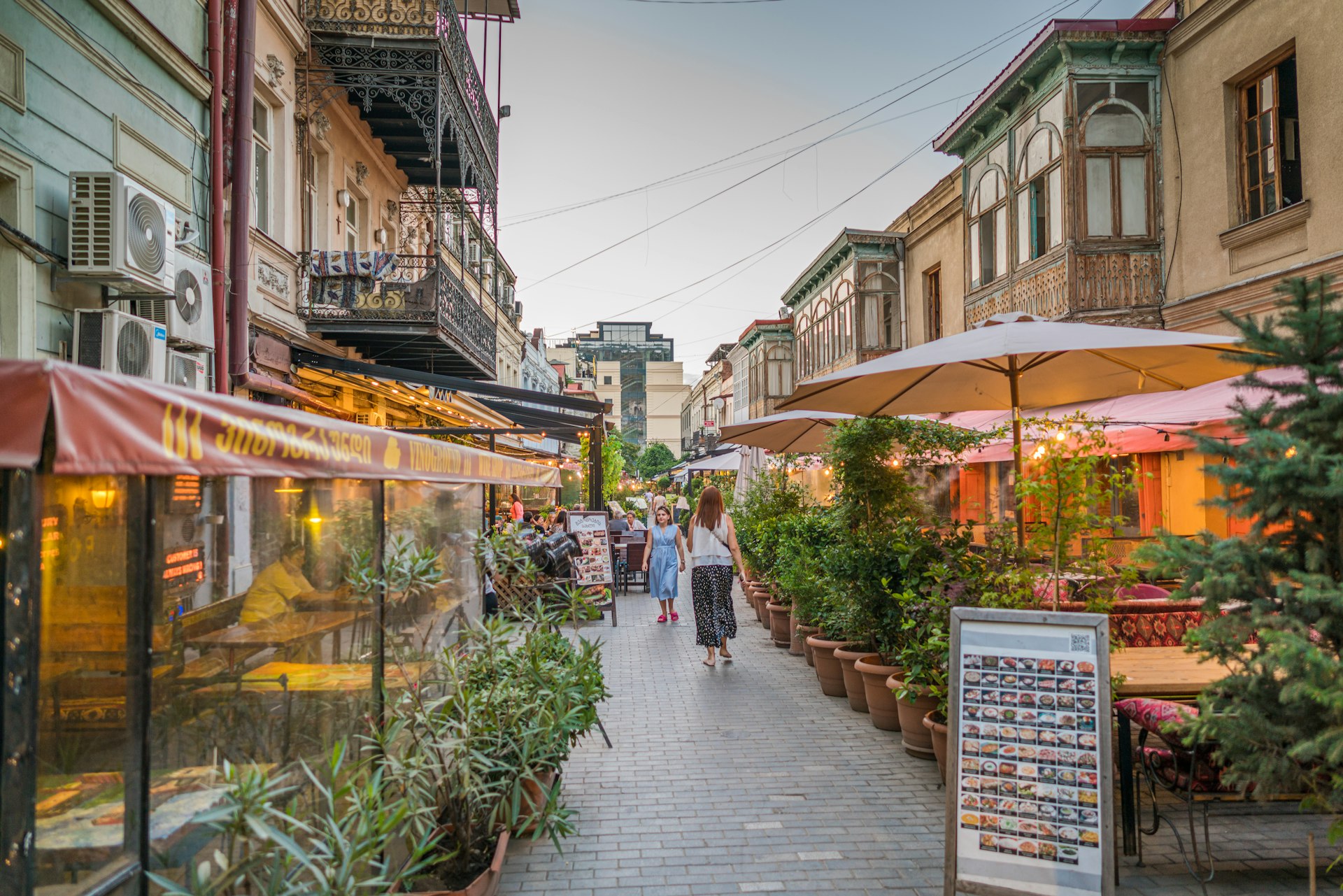 A narrow street lined with bars and restaurants, with tables on the sidewalk, in Tbilisi, Georgia