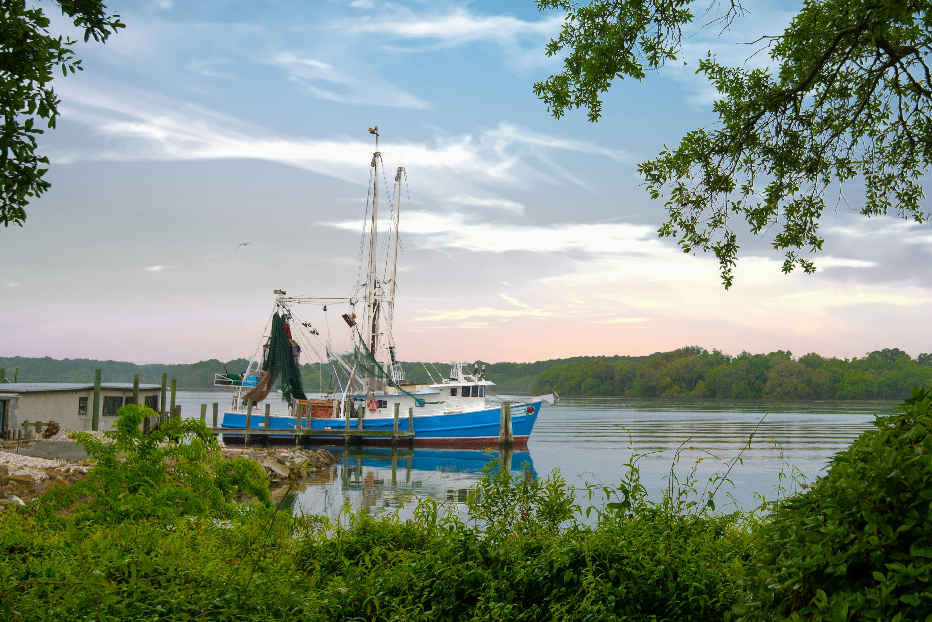 A shrimpboat heading out for fishing from a small wooden dock