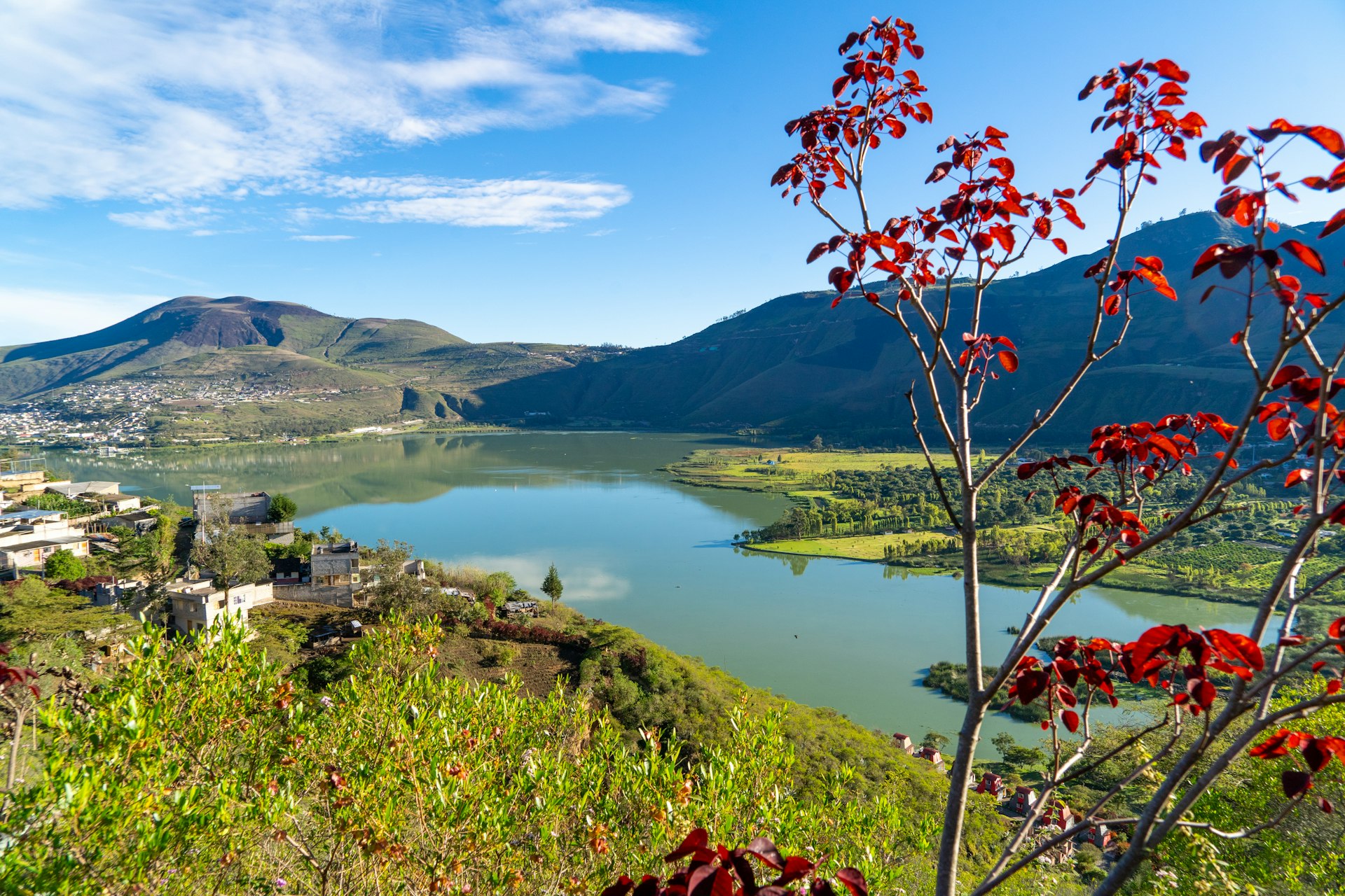 A scenic view over a lake with a few small buildings tucked into the surrounding hillsides