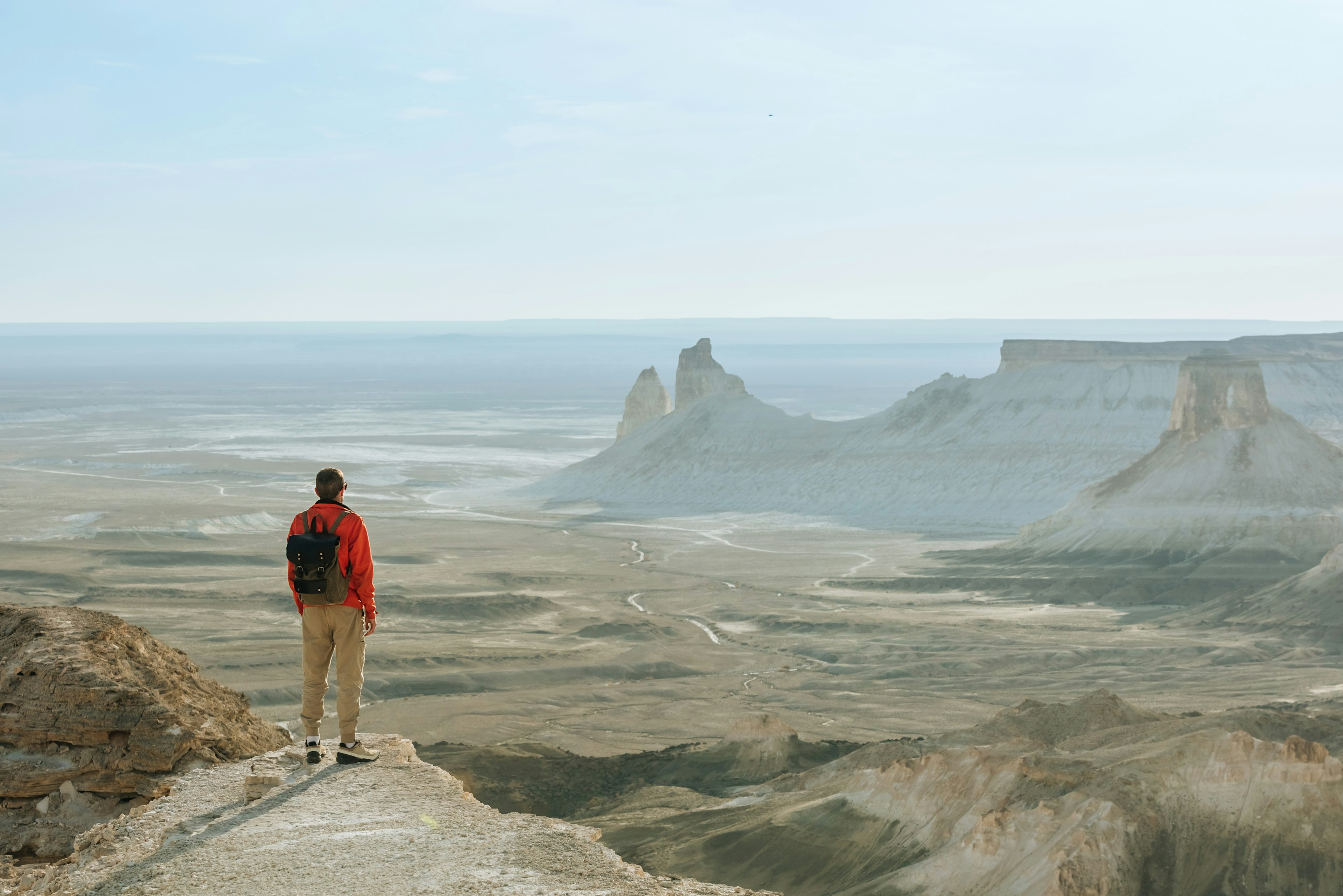 A hiker at the top of a mountain looking out at the mountains of Boszhira, Ustyurt Plateau, Kazakhstan