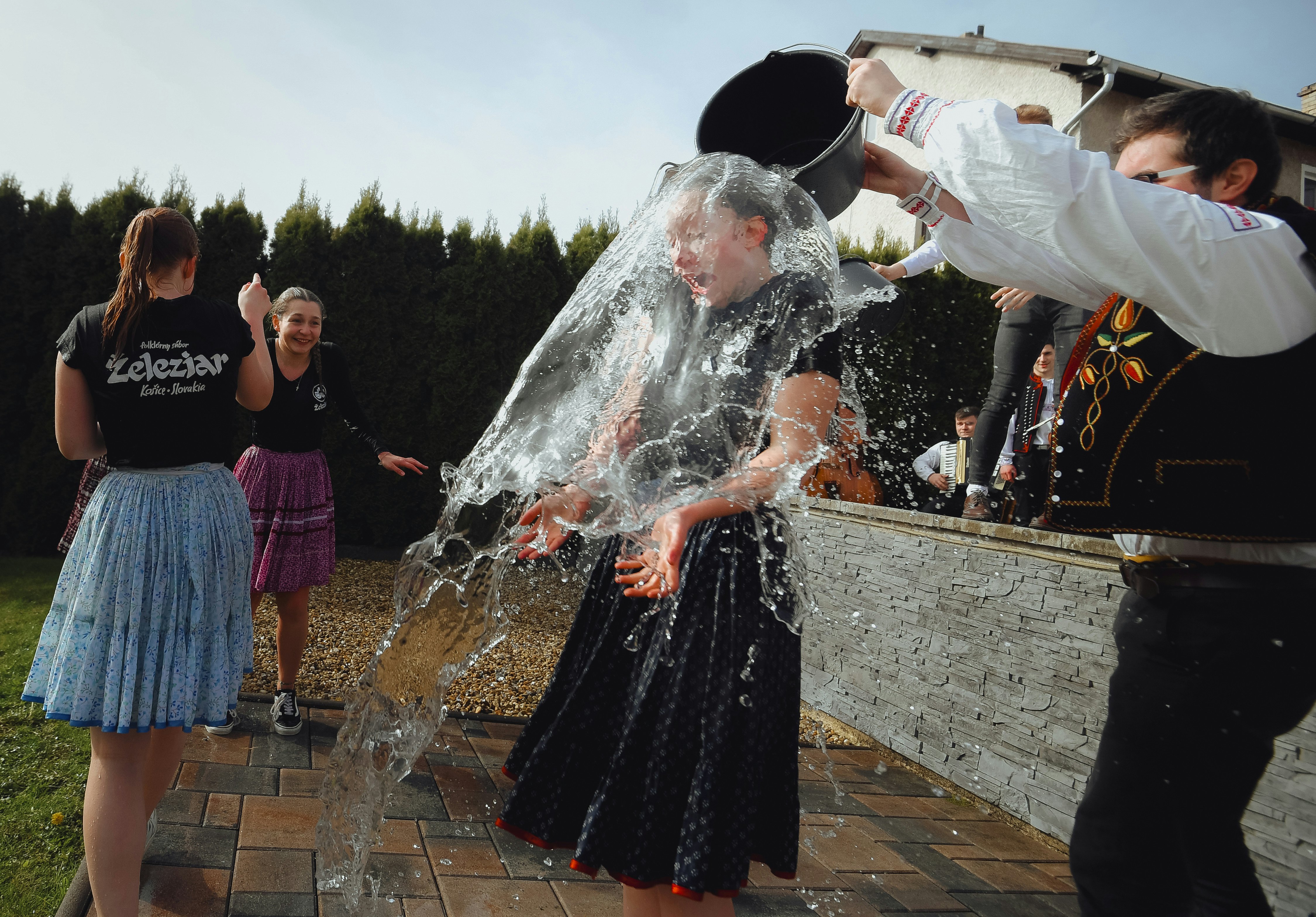Male members of a folk dance group pour water on a girl dressed in traditional clothing in Slovakia.