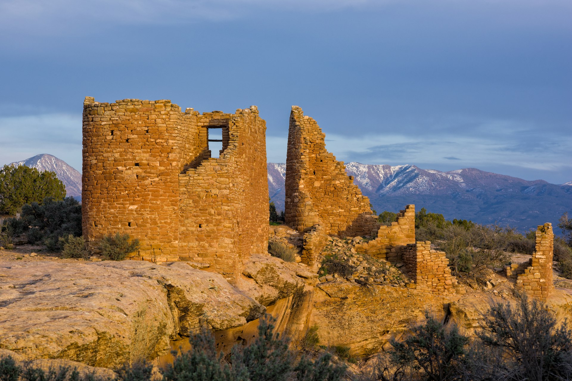 The structure of the Hovenweep Pueblo Ruins are lit up at sunset. 
