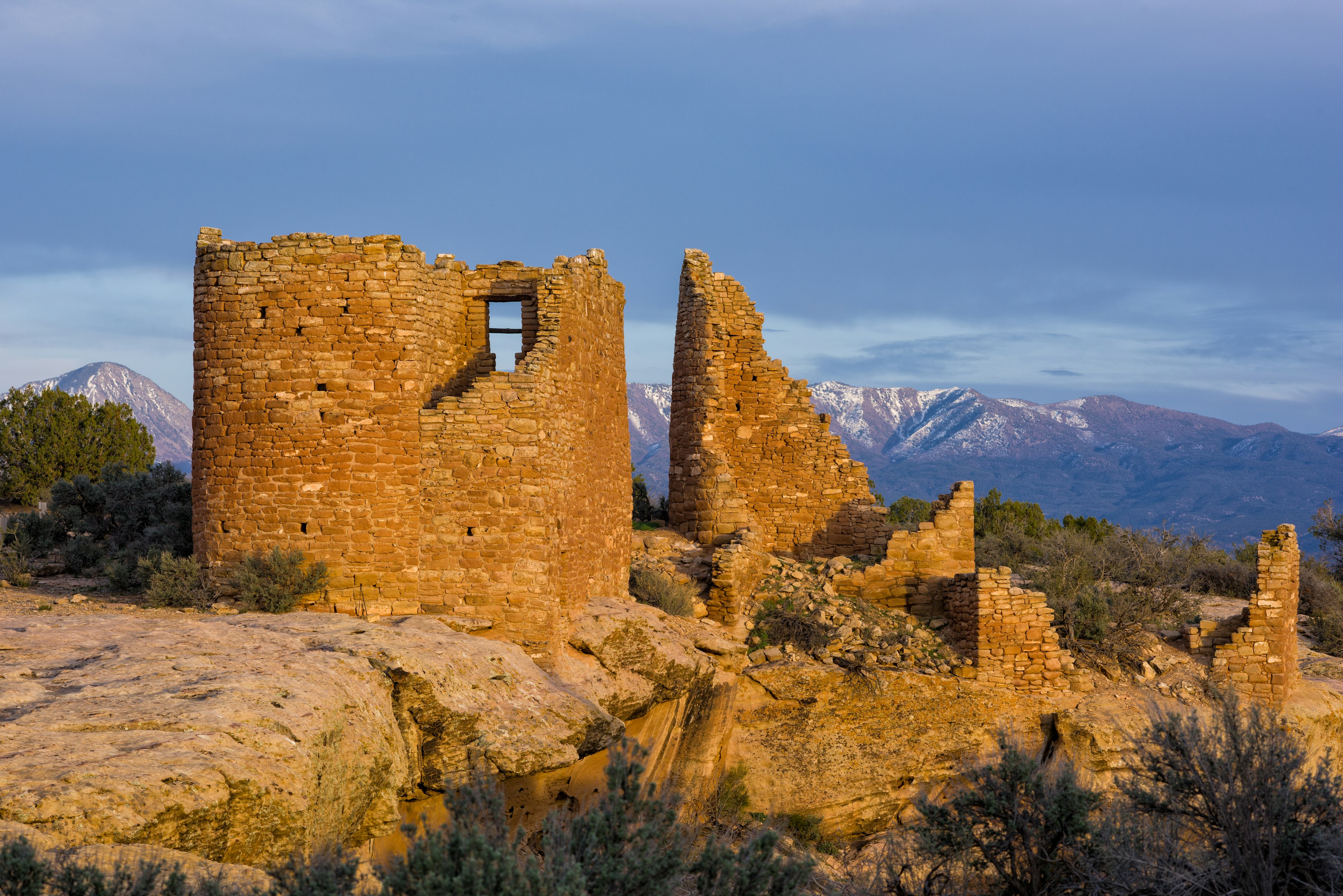 The structure of the Hovenweep Pueblo Ruins are lit up at sunset.