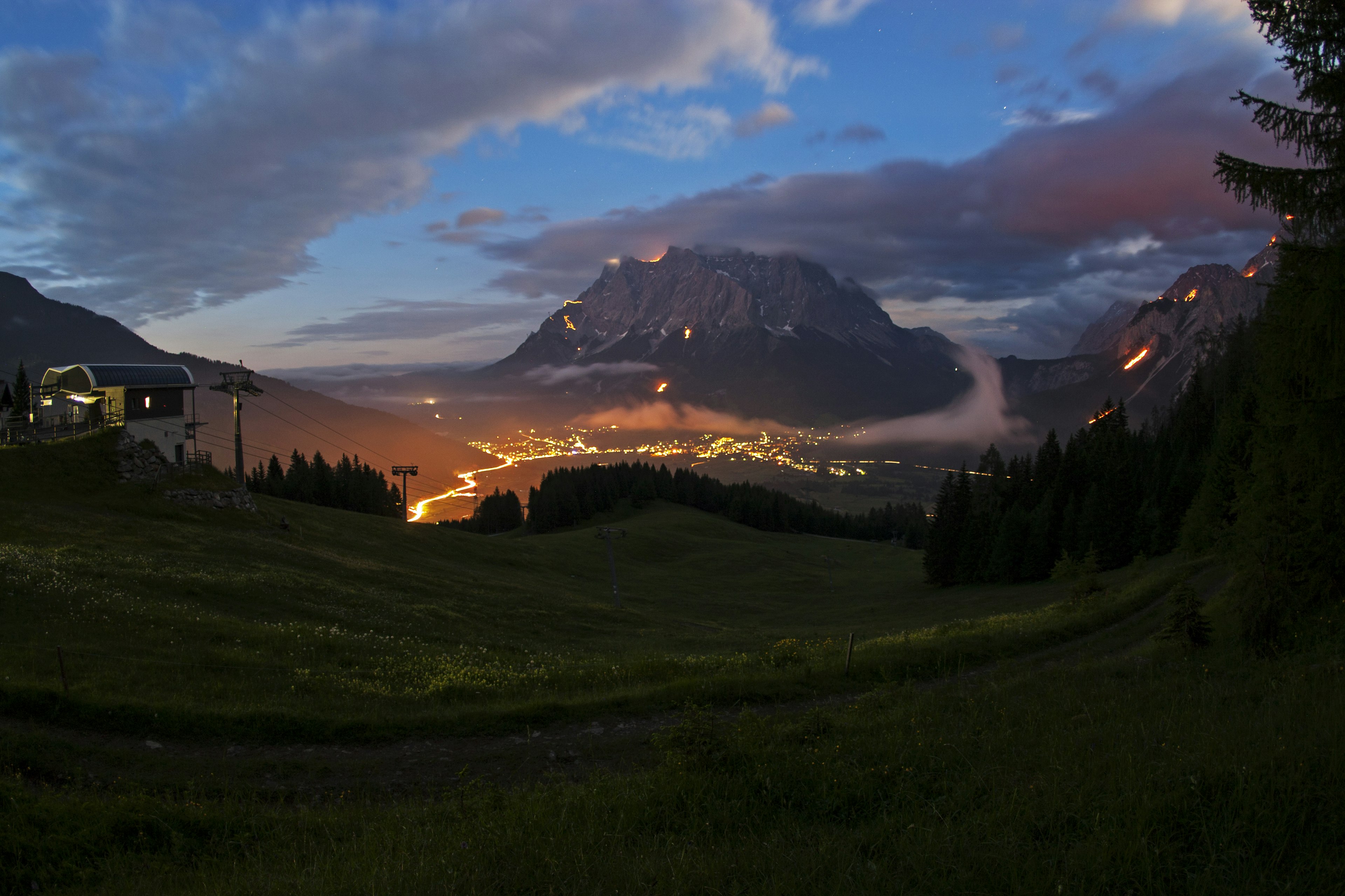 Mountains are glowing red and orange in the darkness, lit by many fires