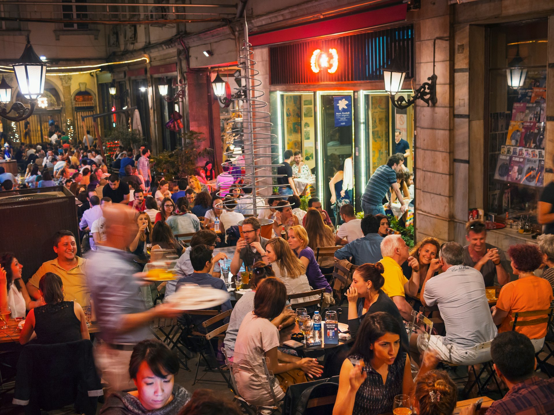 Many people are packed into the outside seating area of a bar in the Beyoğlu district of Istanbul