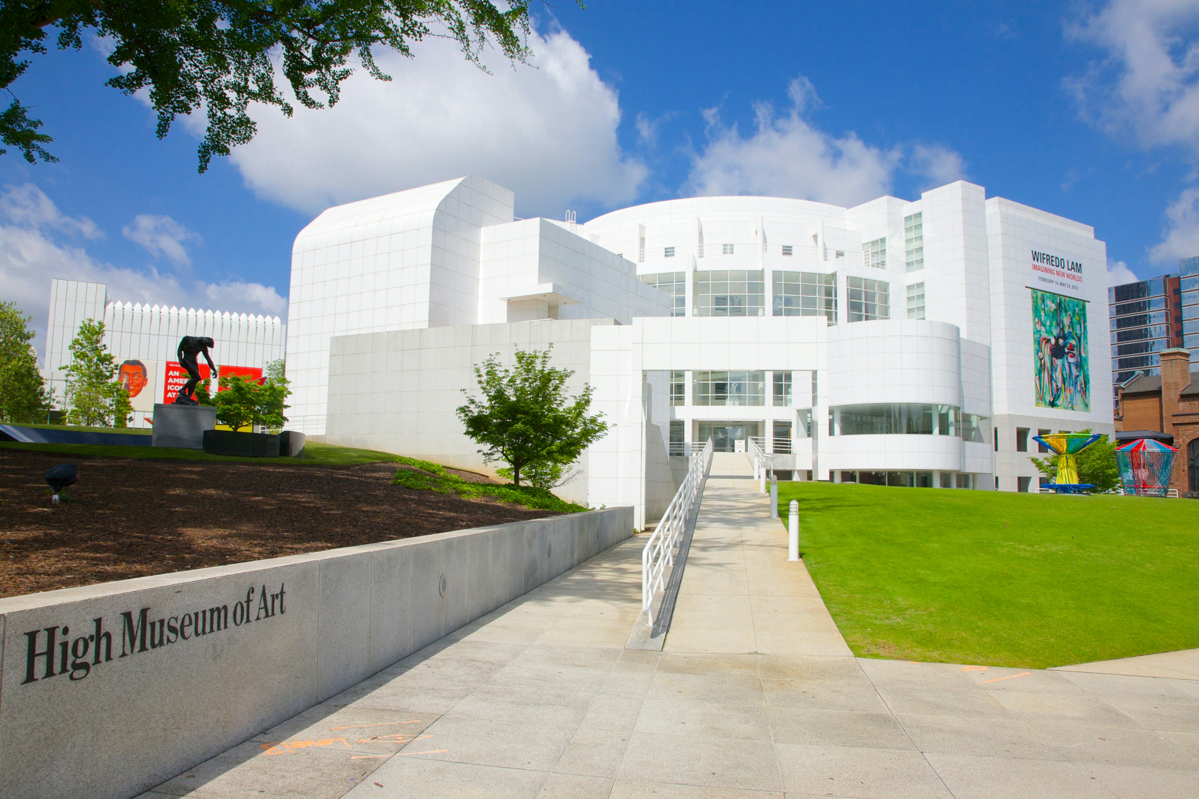 The paved path leading towards the gleaming white building of the High Museum of Art in Atlanta. The name of the museum is etched into a stone wall running alongside the path.