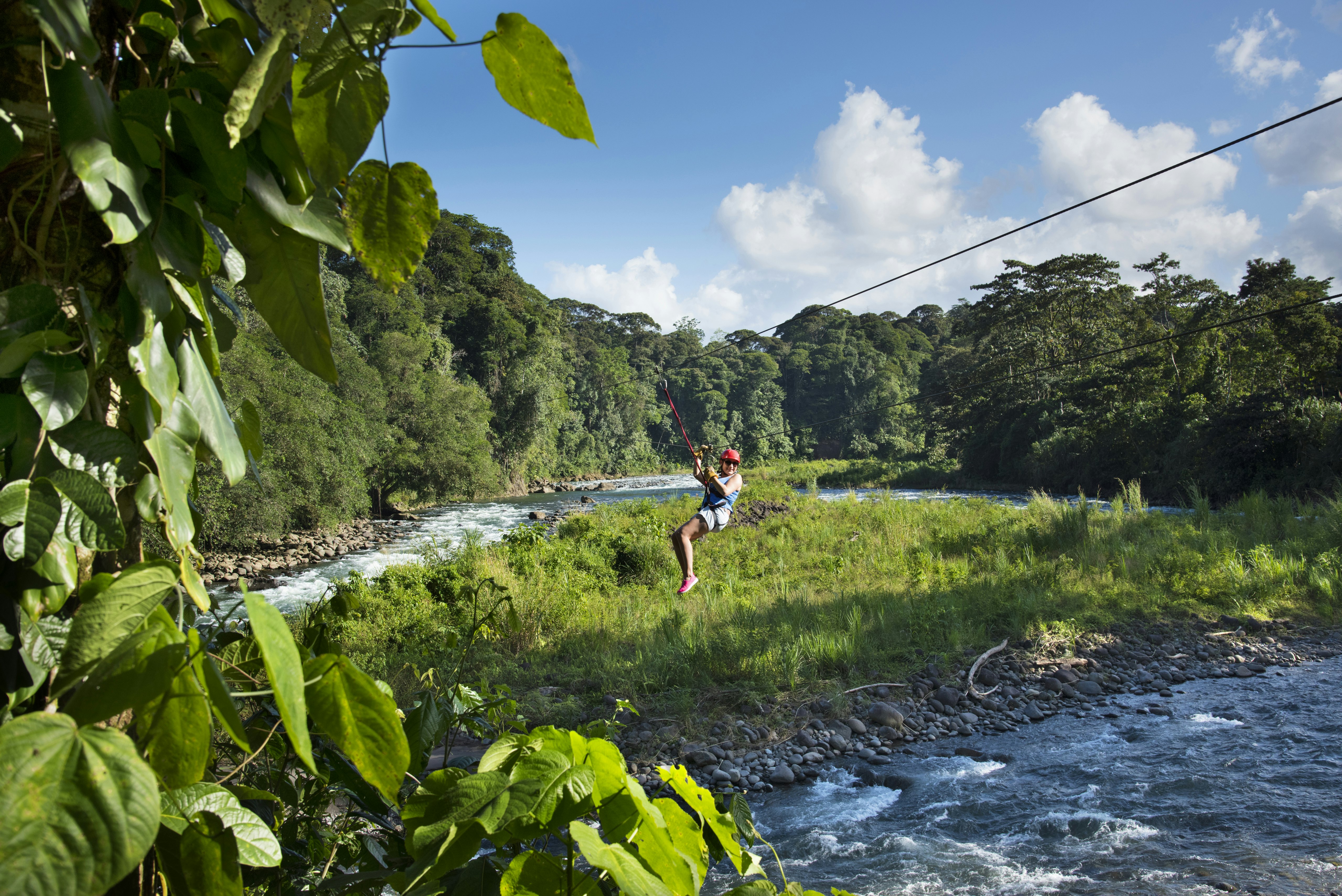 A person on a zip line over a river in Costa Rica.