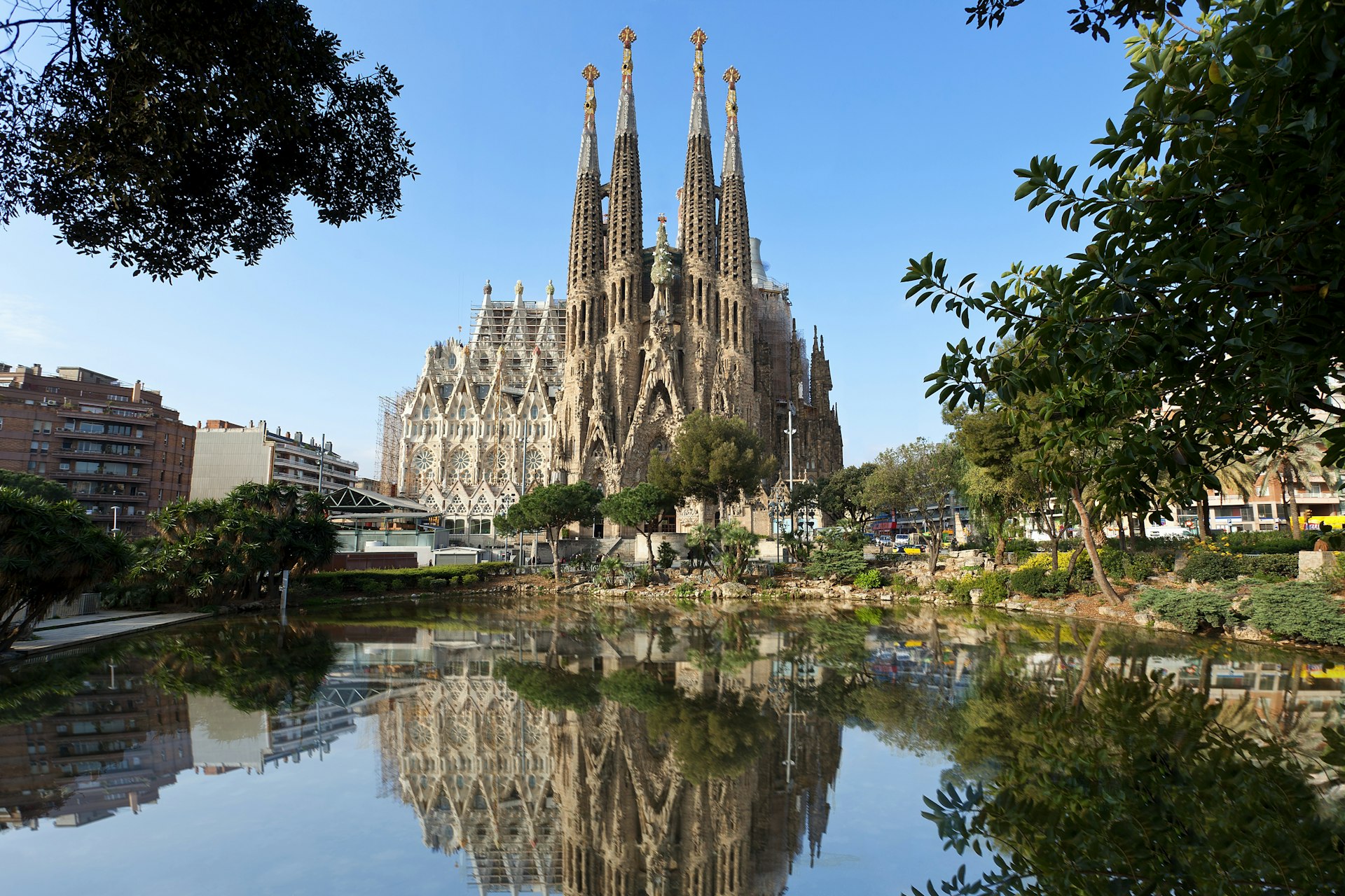 A very tall church with four individual spires reflected in a pond