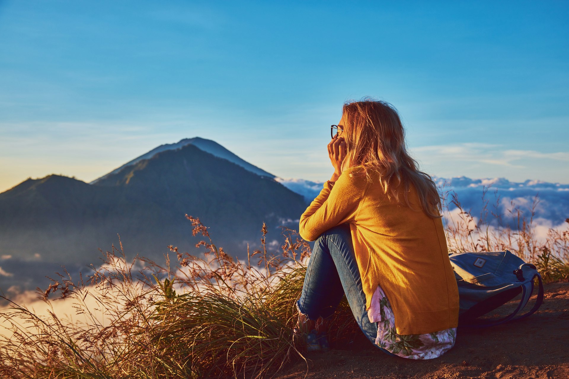 Woman watching the sun rise from the top of Mt Batur, Bali, Indonesia