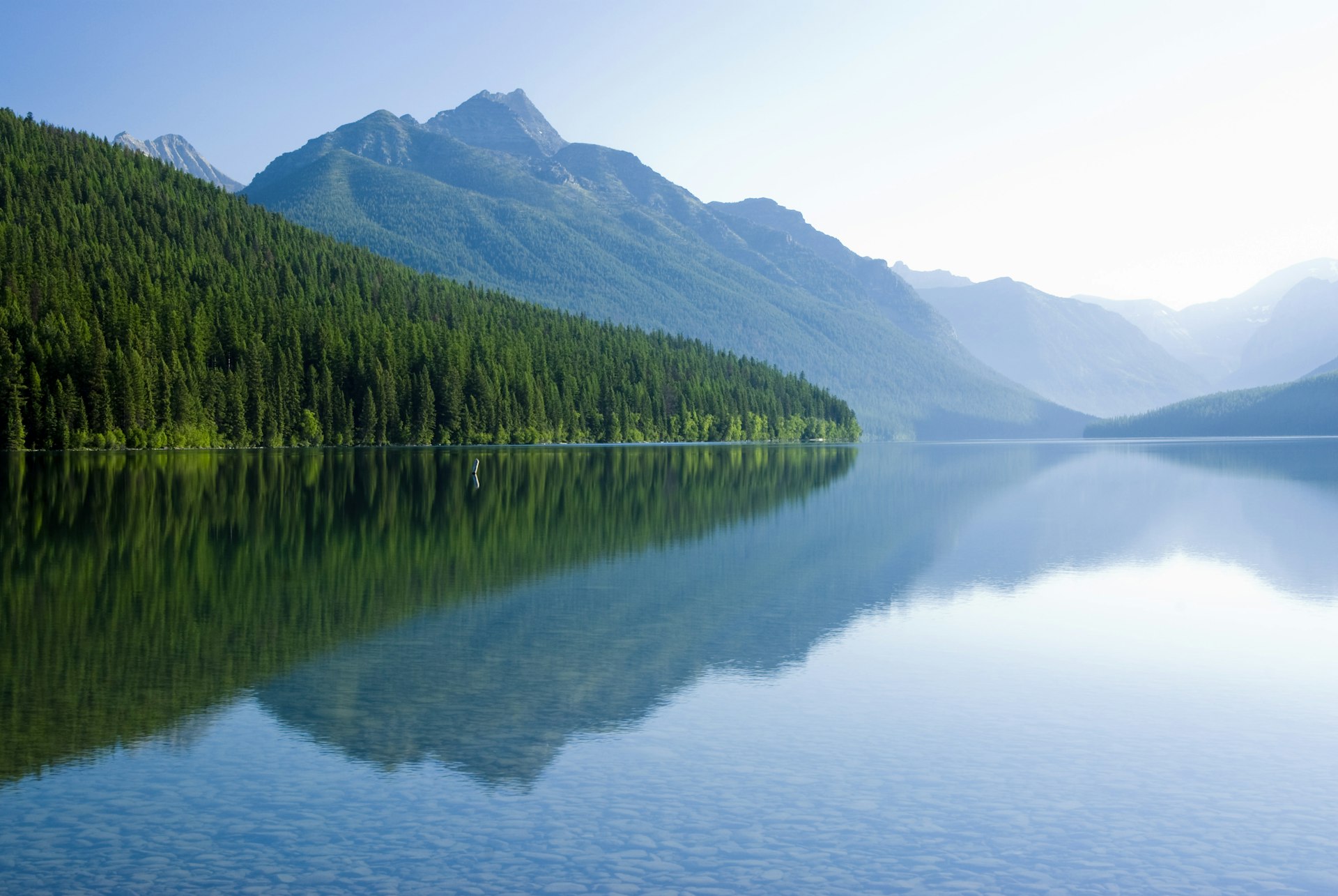 Mountains reflected in a very still, clear Bowman Lake in Glacier National Park