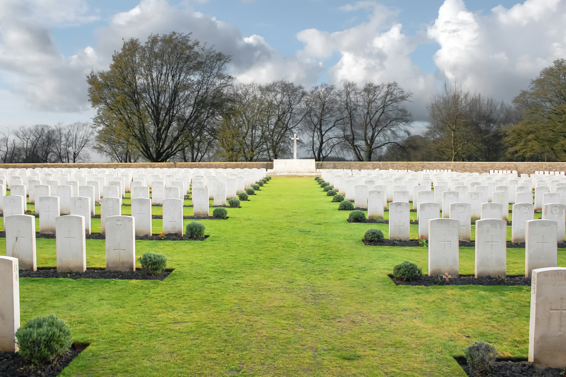 Fileiras de sepulturas brancas num cemitério de guerra