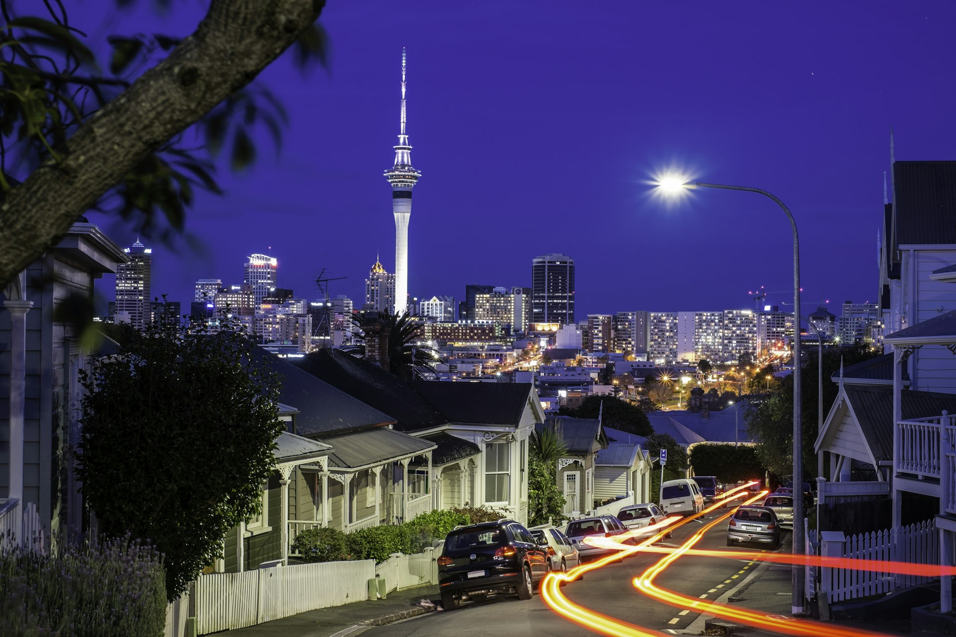 Light Trail Street in Ponsonby, inner-city suburb of Auckland City at dusk. In the background the city centre, and the Sky Tower