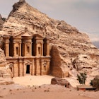 Person stands near the doorway to the Monastery (Ad Deir) in Petra.
972766398
Spirituality, Scenics - Nature, UNESCO World Heritage Site, Architecture, Famous Place, International Landmark, Looking At View, Extreme Terrain, UNESCO, Monument, National Landmark, Petra - Jordan, Stone Material, Tourist, Ma'an Governorate, Building Exterior, Tomb, Archaeology, Sand, Desert, No People, Middle East, Jordan - Middle East, Mountain, Hiding, Middle Eastern Culture, Ancient Civilization, Facade, Monastery, Carving - Craft Product, Large, Travel Destinations, Horizontal, Wadi Musa, Temple - Building, Landscape - Scenery, Red, Al Deir Temple, Cultures, Color Image, Stone - Object, History, Sandstone, Indigenous Culture, Jordan, Ancient, Old, Adventure, Rock - Object, Photography, Built Structure, The Past, Sky, Nature