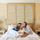 Mature couple in their 40's enjoying wine in hotel room at luxury resort in Napa Valley, California. Couple lying on bed relaxing, talking, and smiling.