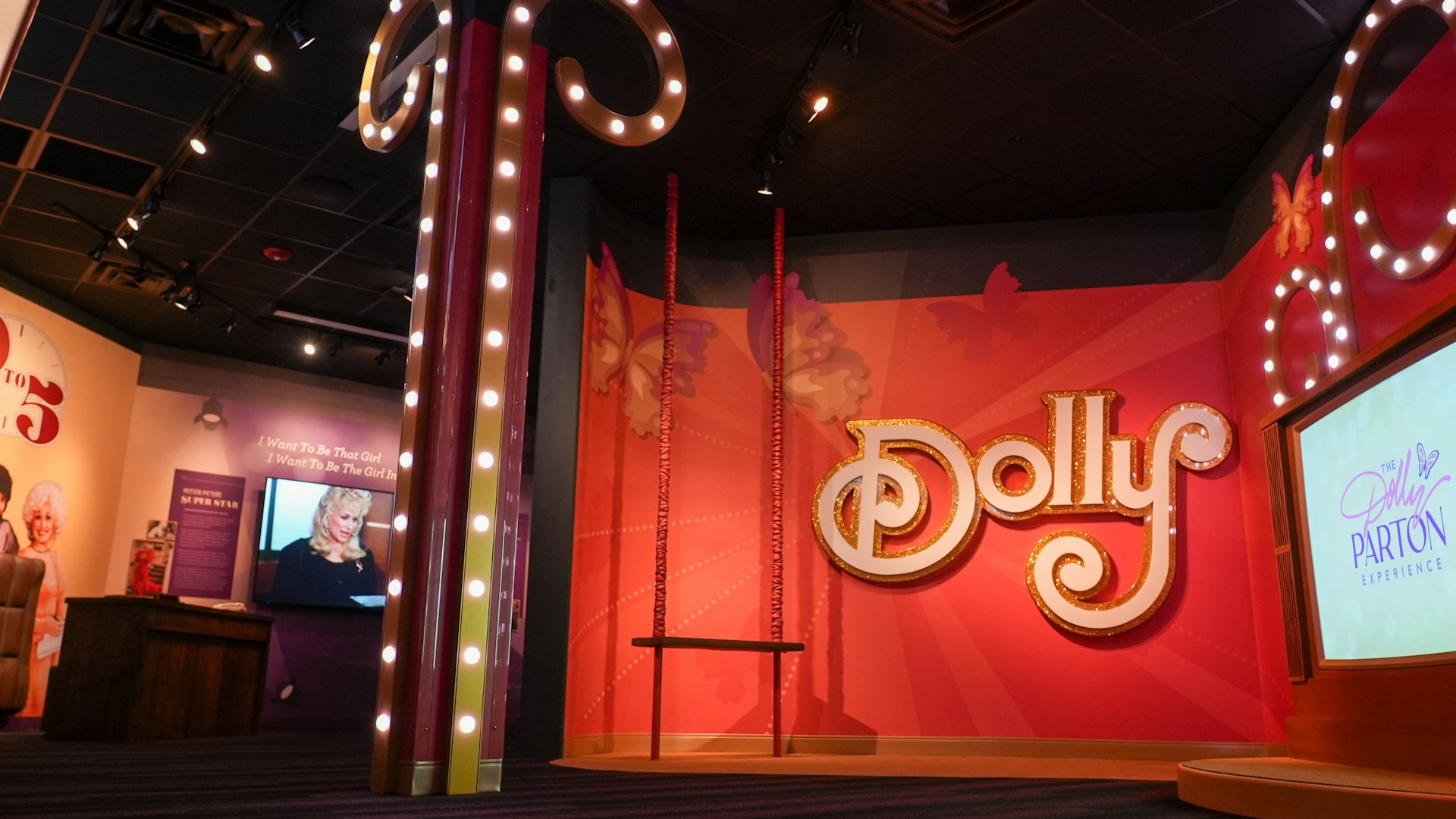 A large orange sign with "Dolly" written on it, next to a TV screen and interactive exhibits