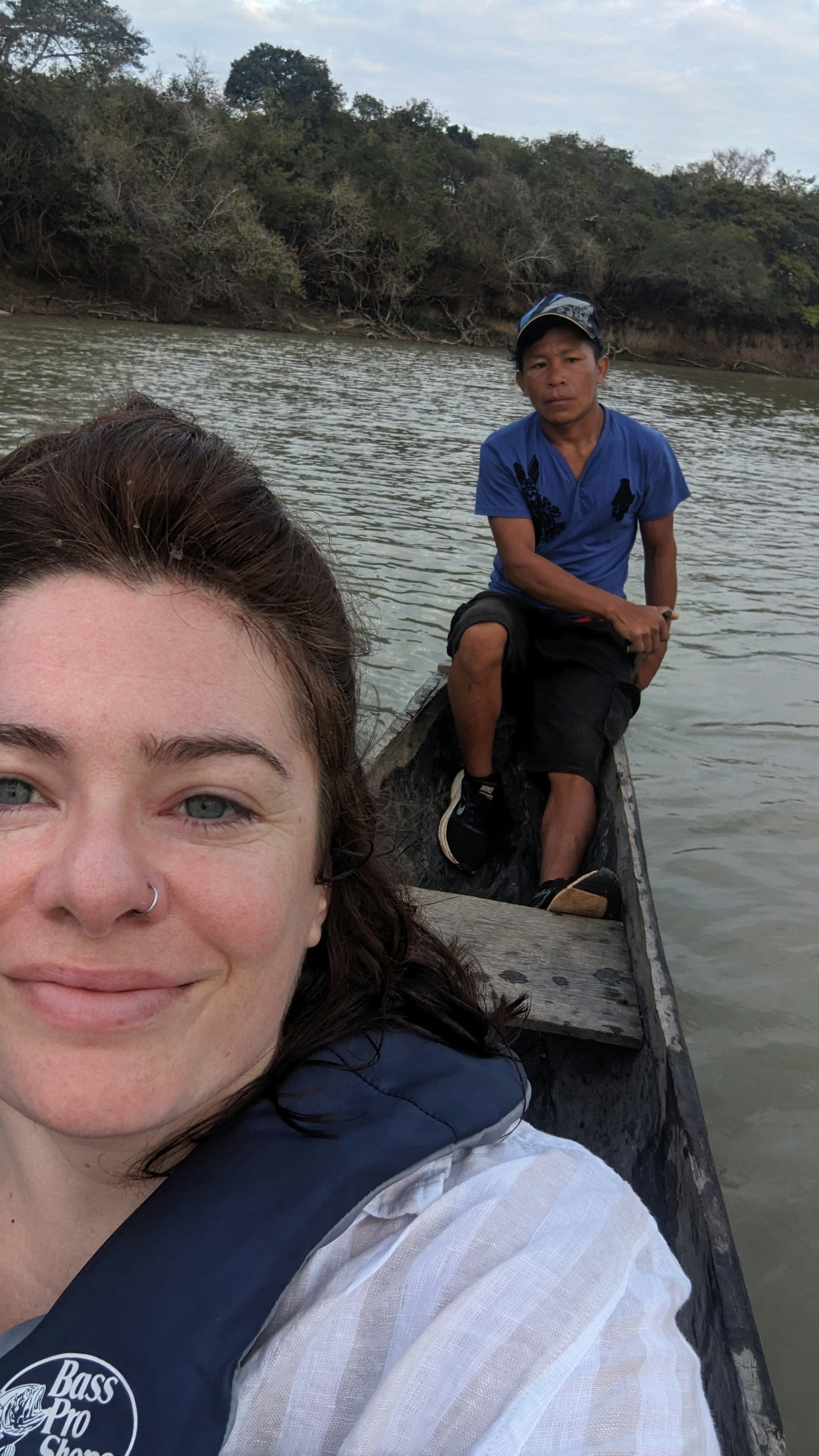 Traveller on a boat tour with a guide in Guyana both looking at camera 