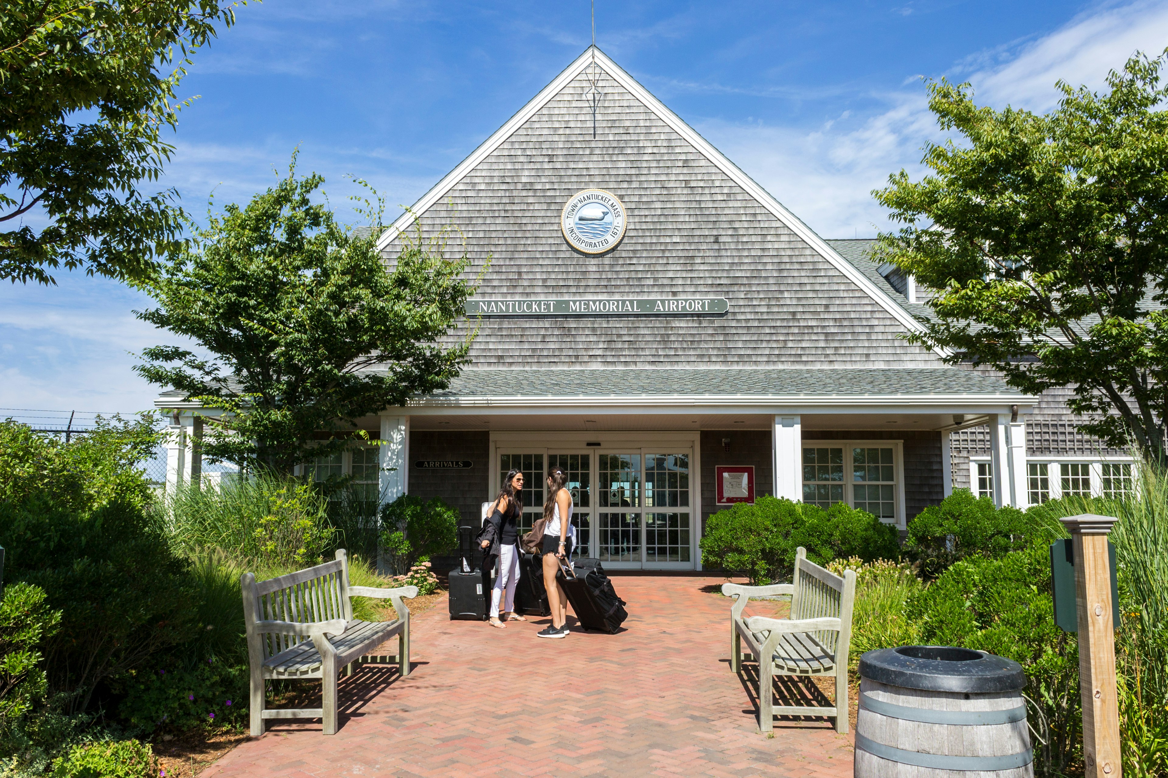 Two people with luggage outside a small quaint airport building