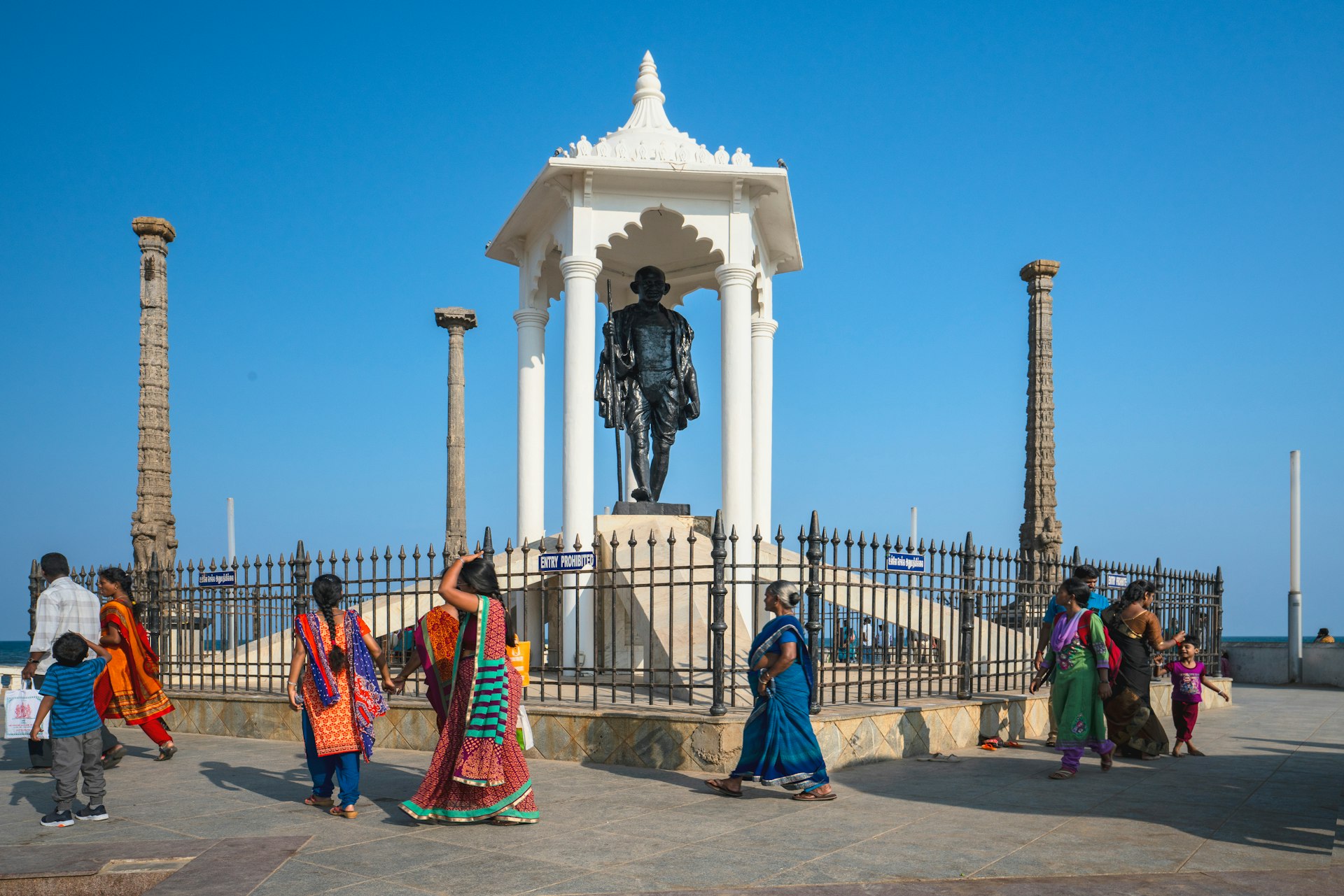 People walk by the Gandhi Memorial on at the promenade beach front, Pondicherry, India