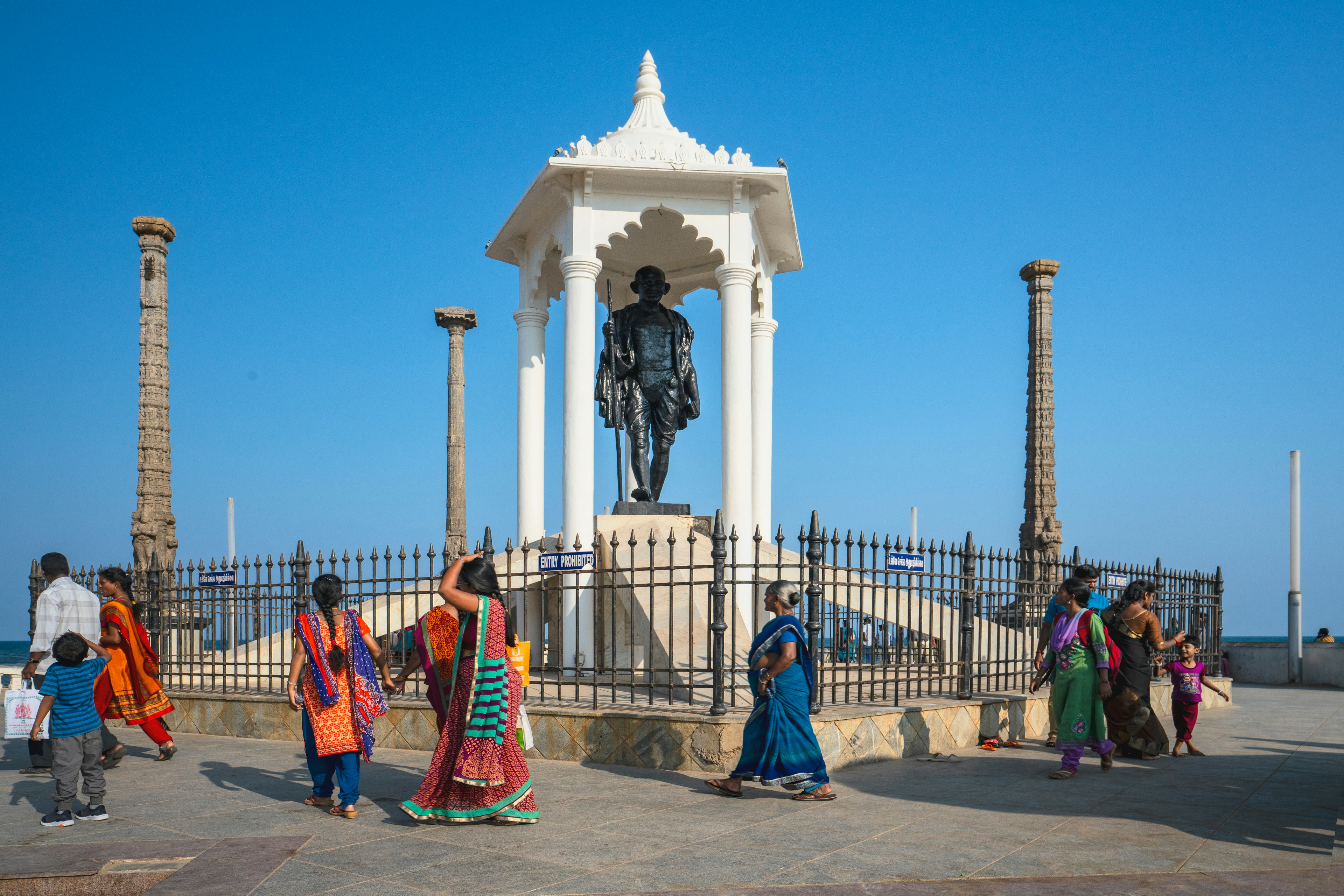 People walk by the Gandhi Memorial on at the promenade beach front, Puducherry, India