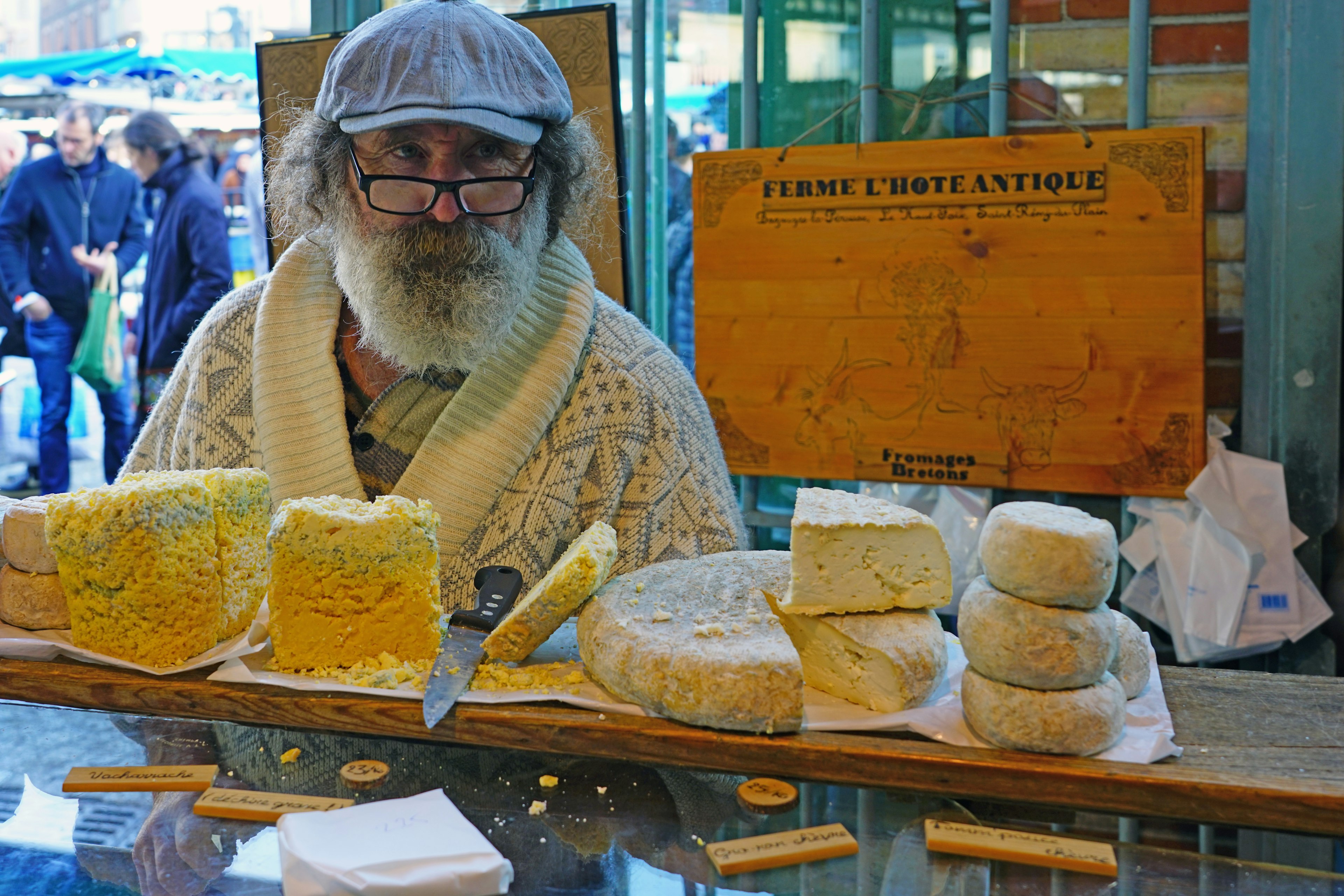 A man with a white beard sells cheese at the Marché des Lices, Rennes, Brittany, France