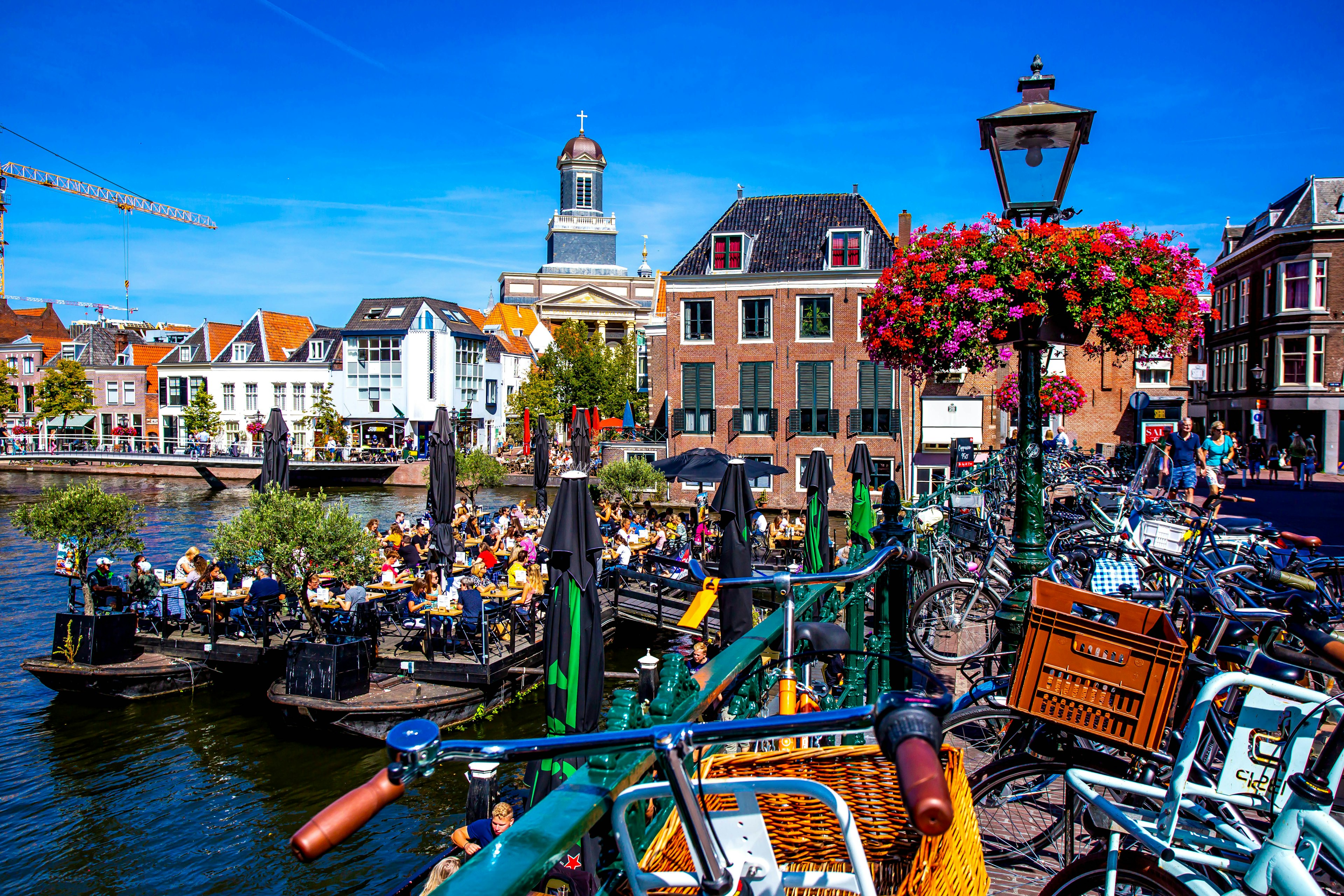 People on a floating barge with drinks in a canal in central Leiden, South Holland, Netherlands