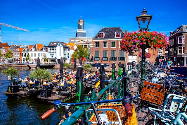 People on a floating barge with drinks in a canal in central Leiden, South Holland, Netherlands