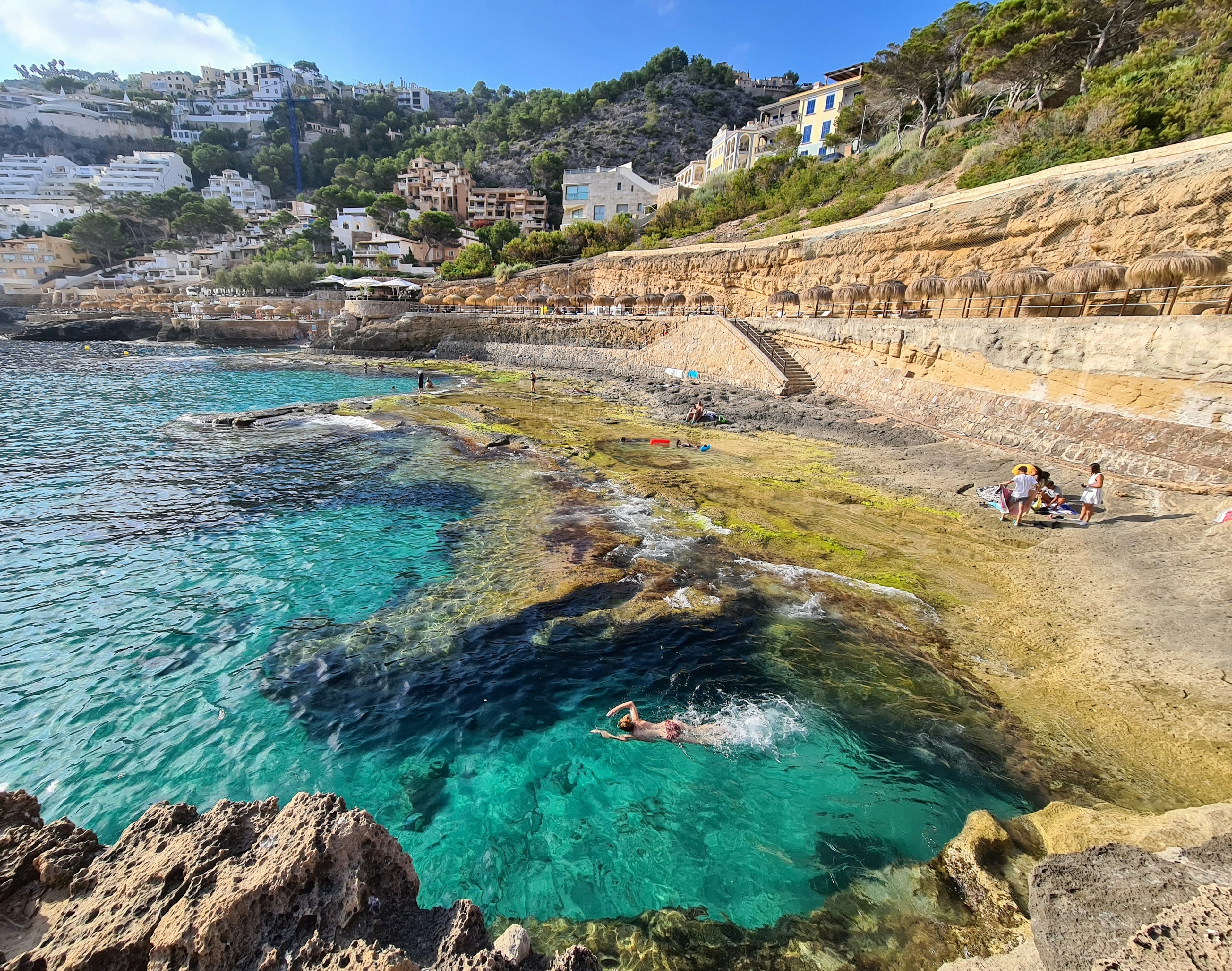 A swimmer heads out from a rocky cove into the sea