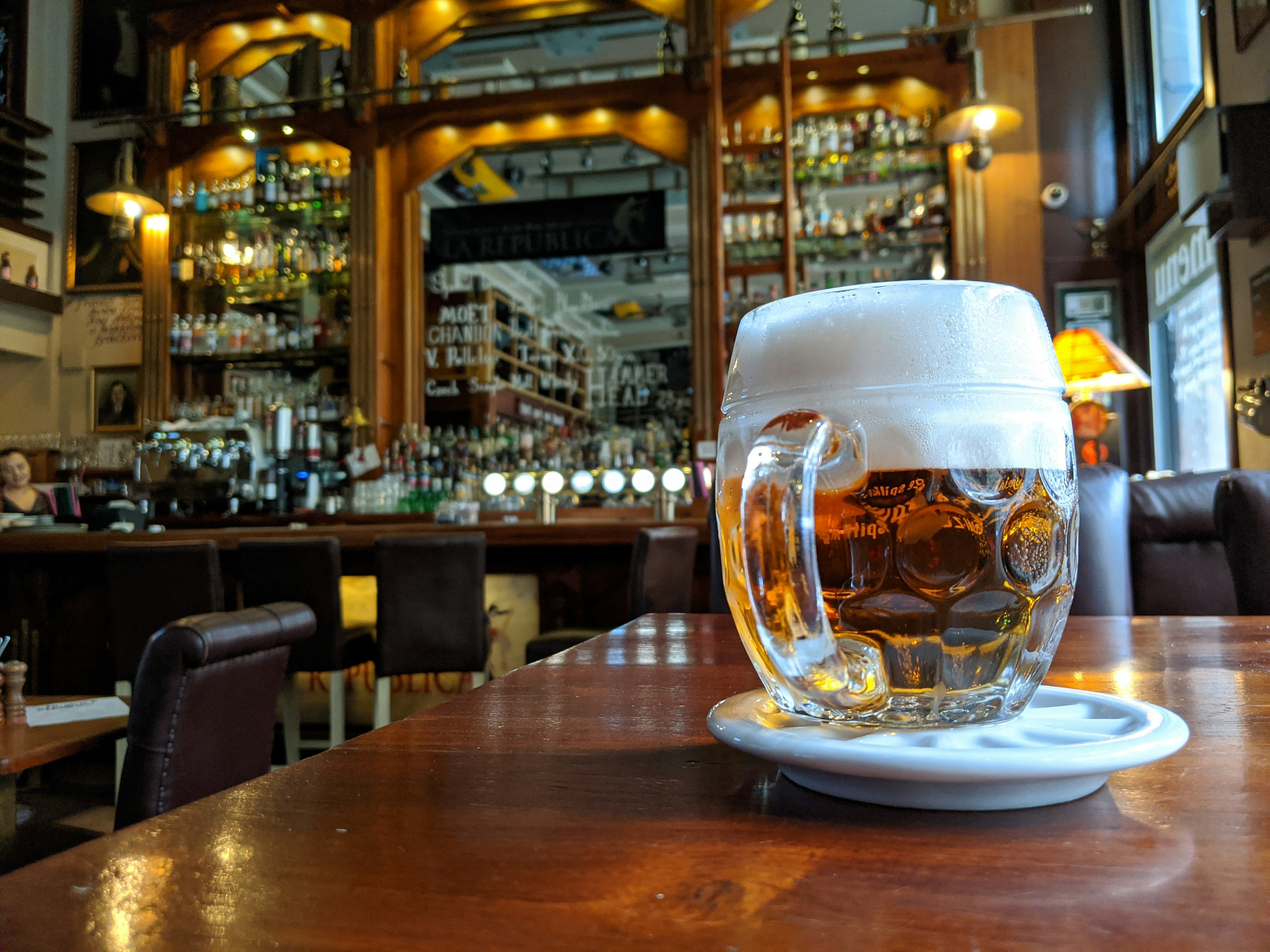 A large jug of beer with a frothy head on a table in a pub