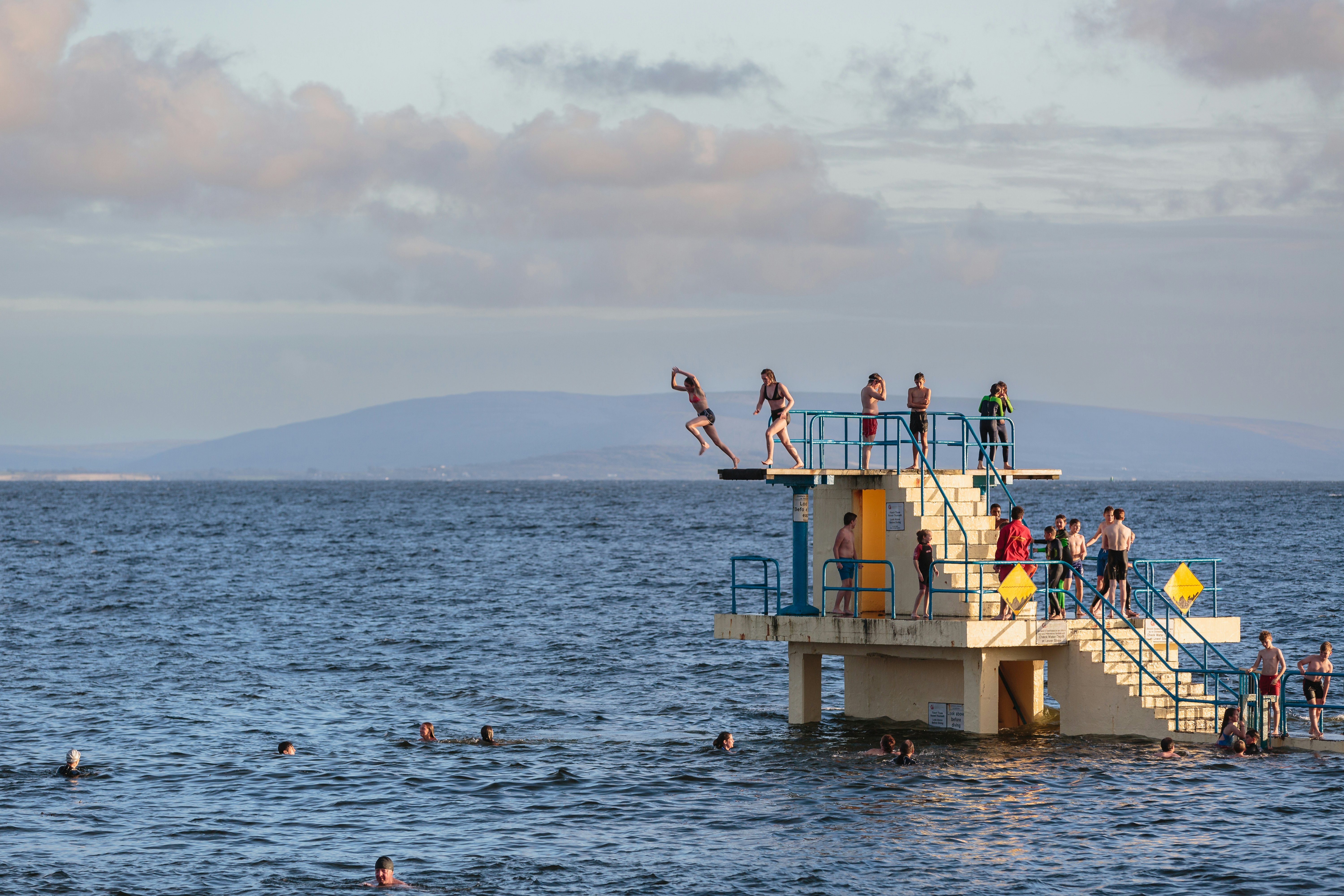 People dive from the Blackrock Diving Tower in Galway at high tide.