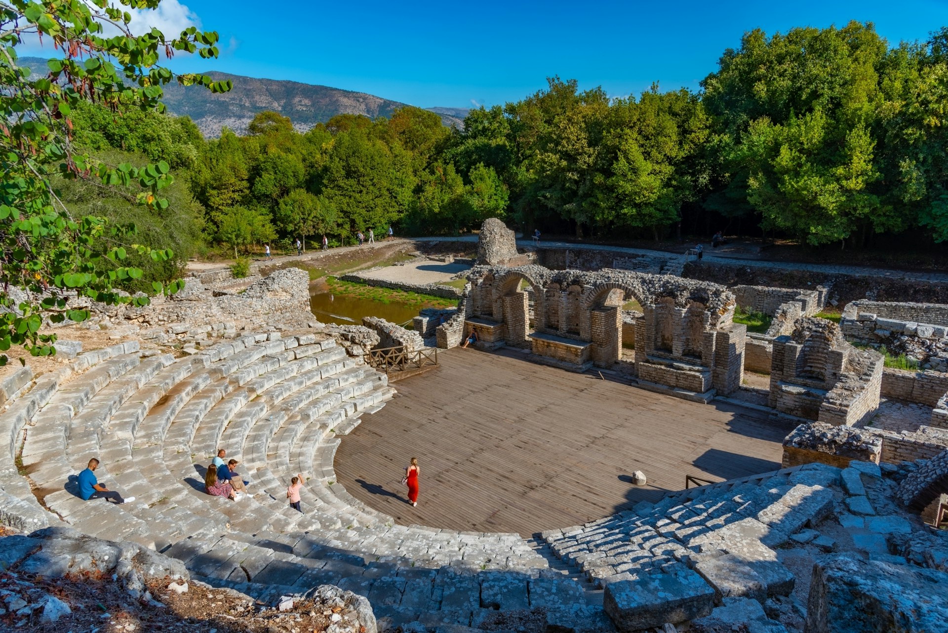 A Roman amphitheater with a handful of tourists admiring the architecture