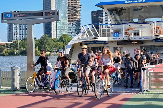People on bicycles riding off a shuttle ferry service on the waterfront in Amsterdam, Netherlands