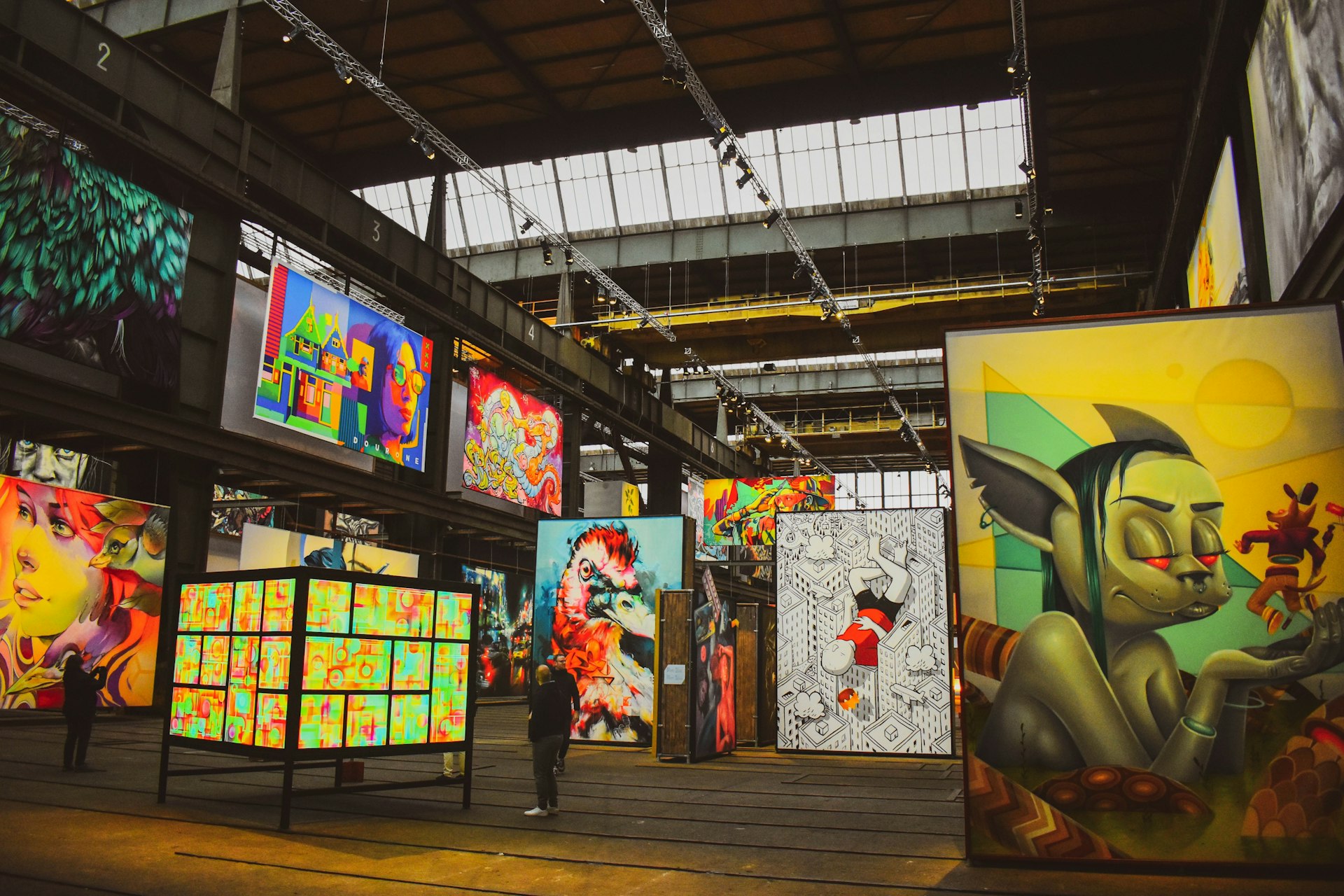 People gaze at vast displays of street art and graffiti in a warehouse-like gallery space