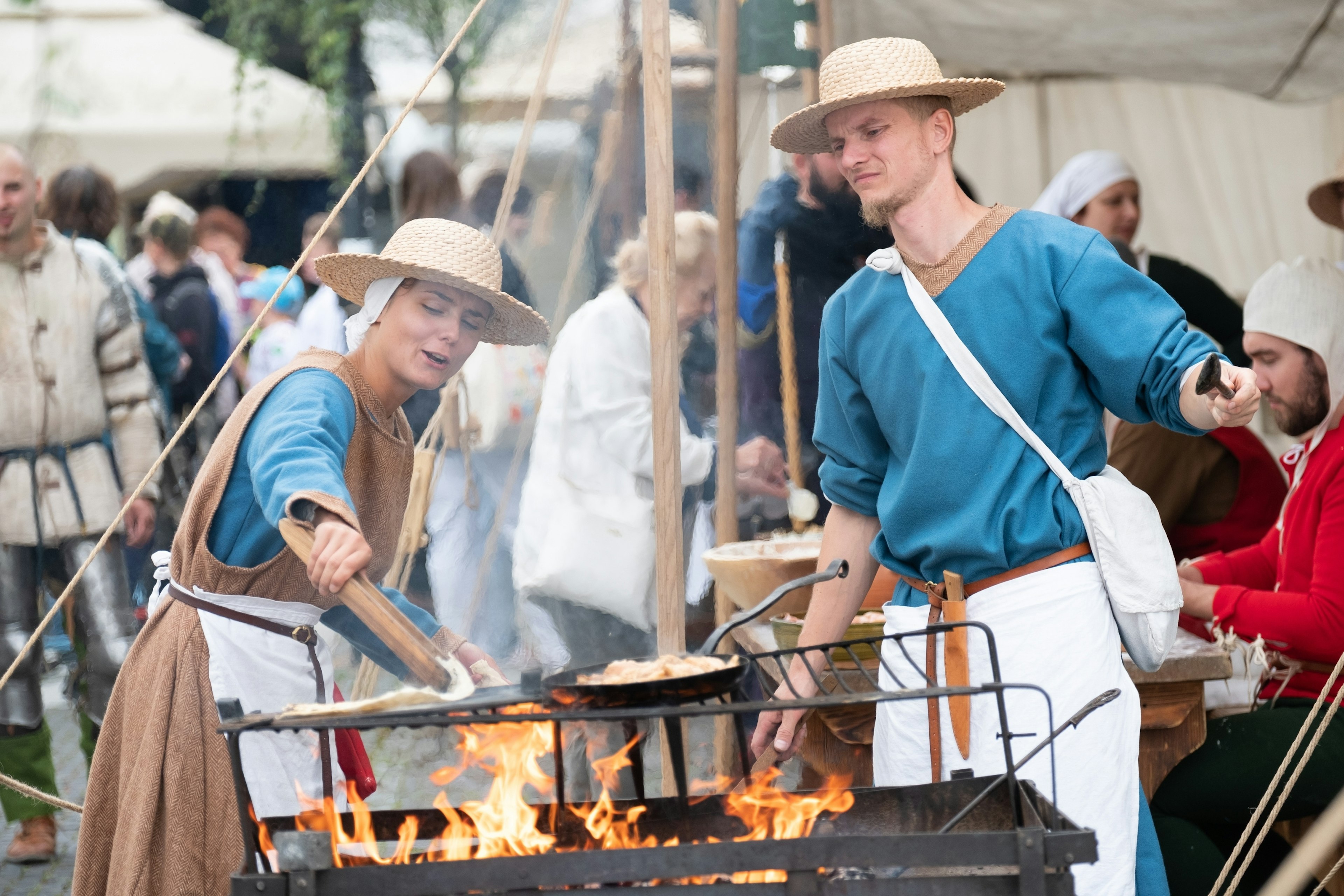 A man and woman in traditional dress prepare flatbread on a grill during a festival in Zilina, Slovakia