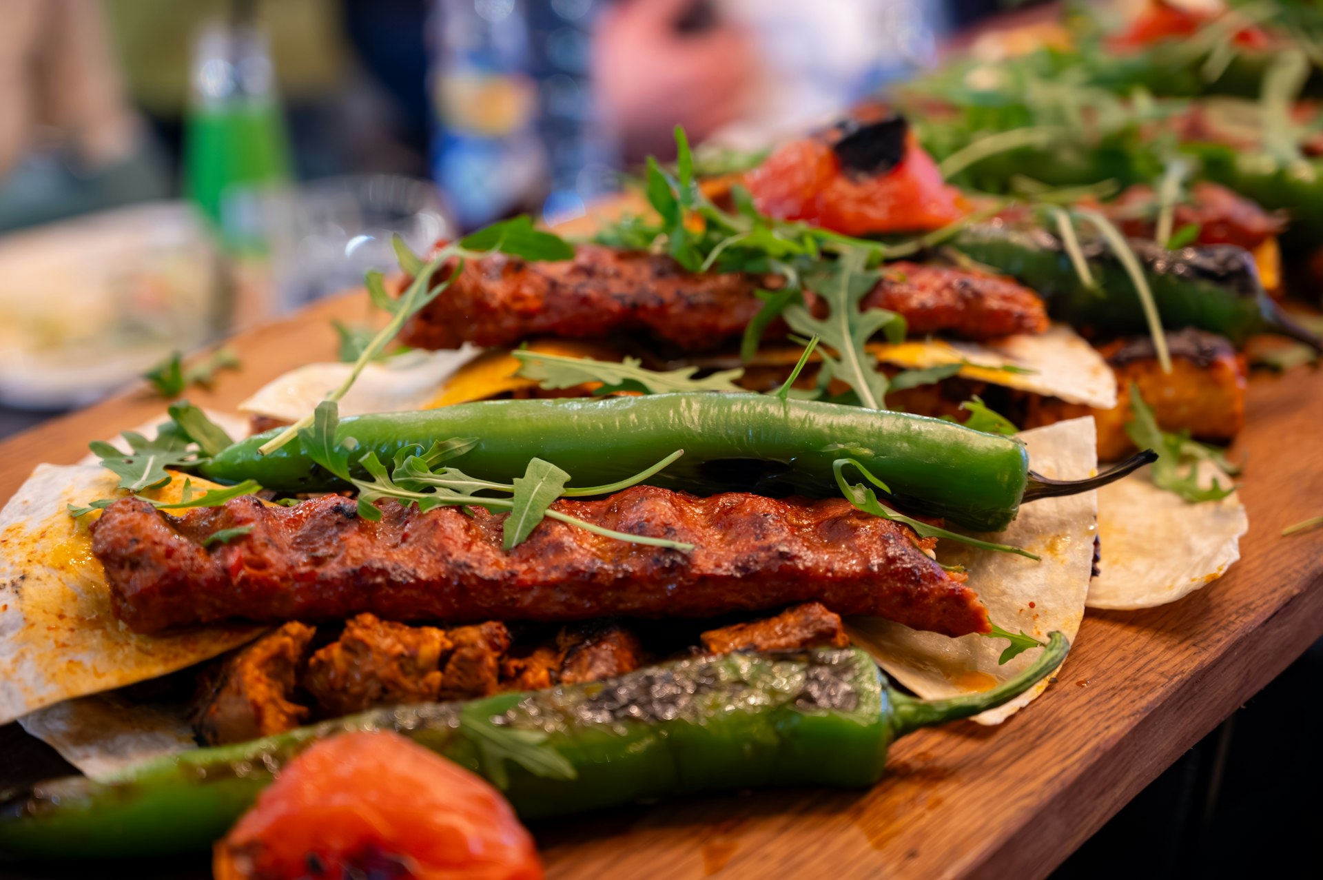 A wooden serving board with Turkish mixed grill meat and green peppers