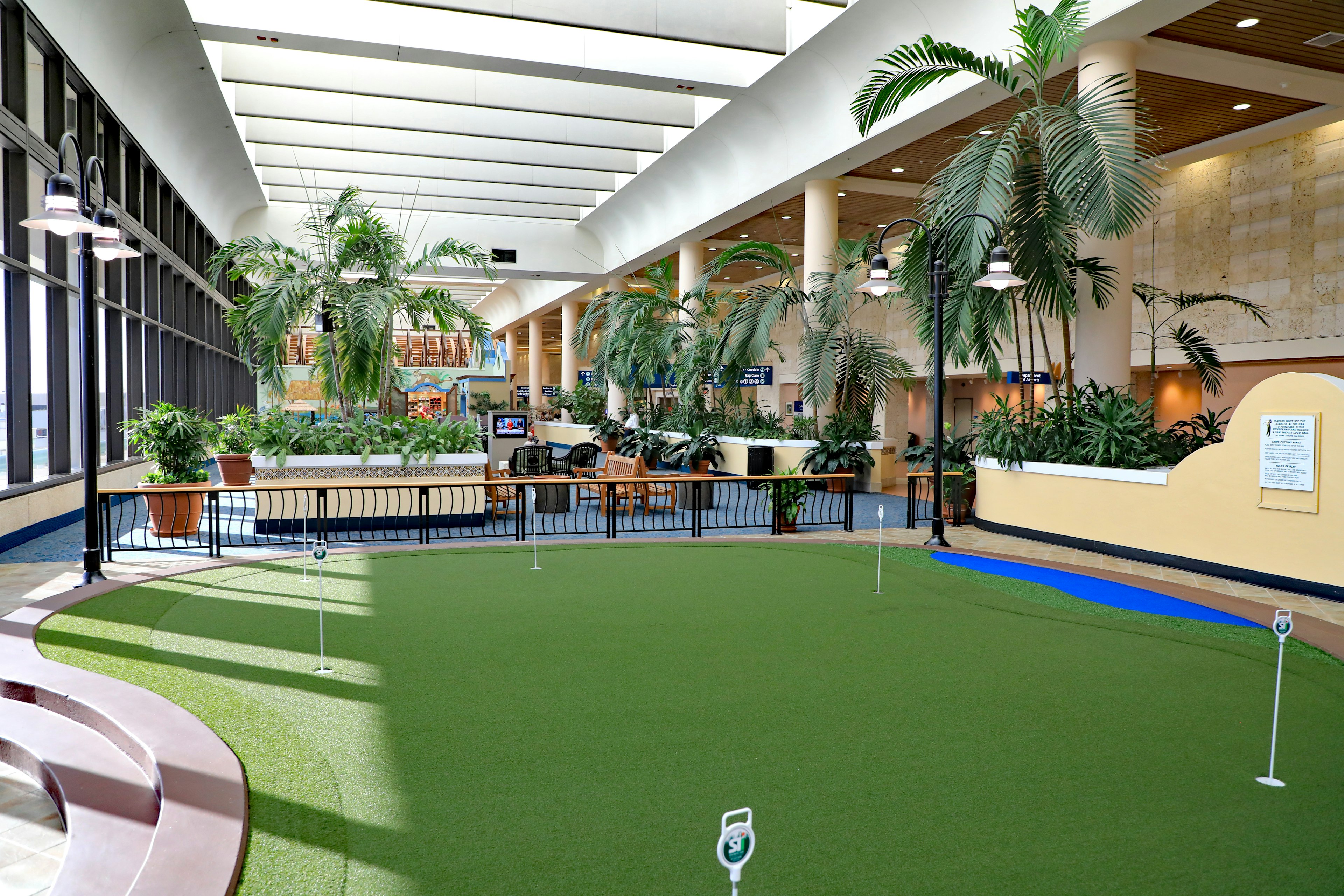 A small putting green lined with palm trees in an aiport