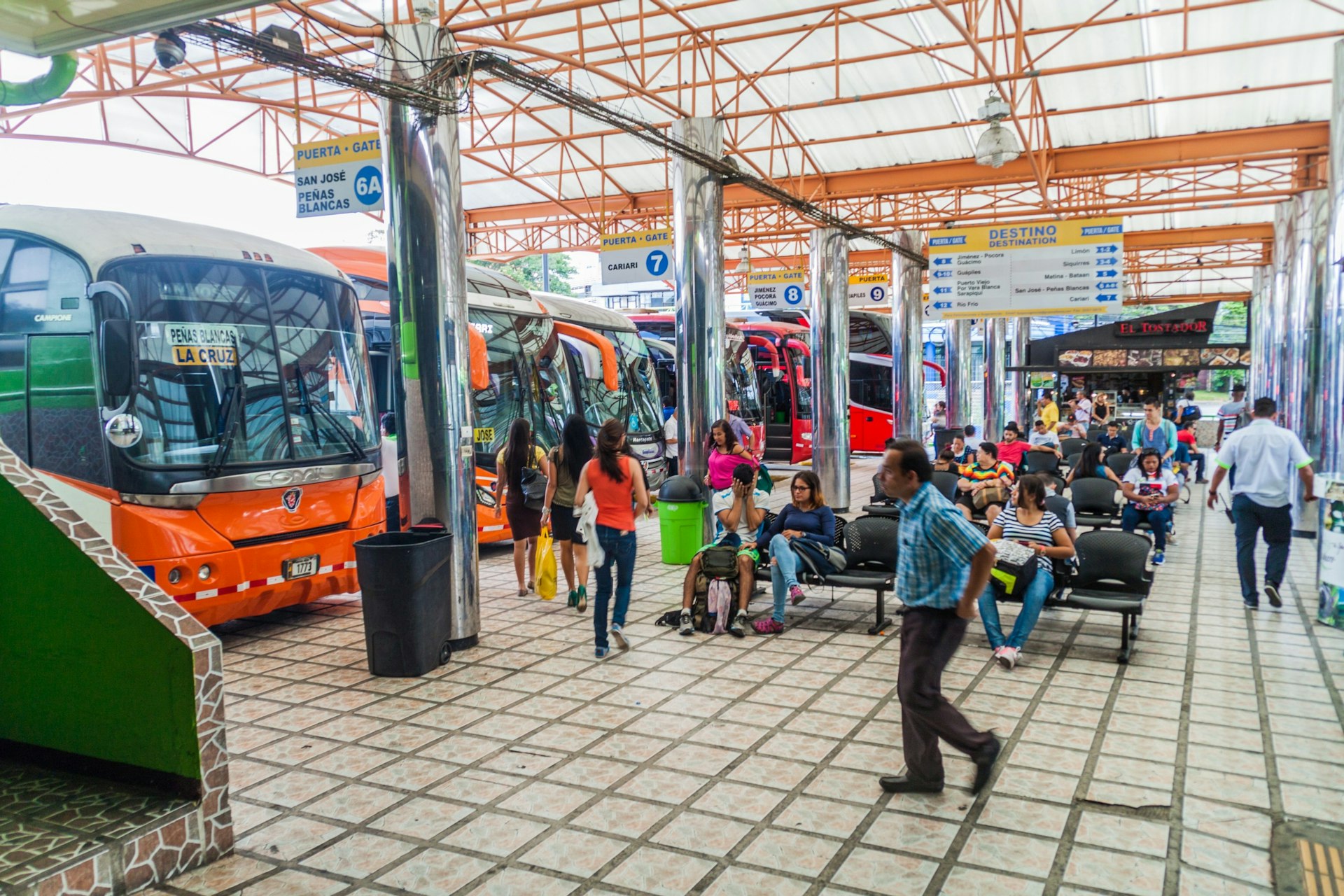 Many people mill around and wait to board the buses parked up at the Gran Terminal del Caribe bus station San José, Costa Rica
