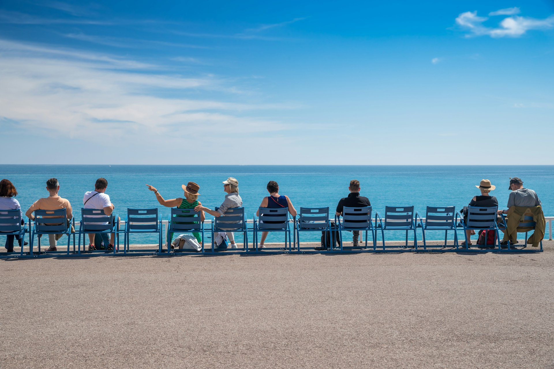 People sit on chairs along the waterfront in Nice, Côte d’Azur, France
