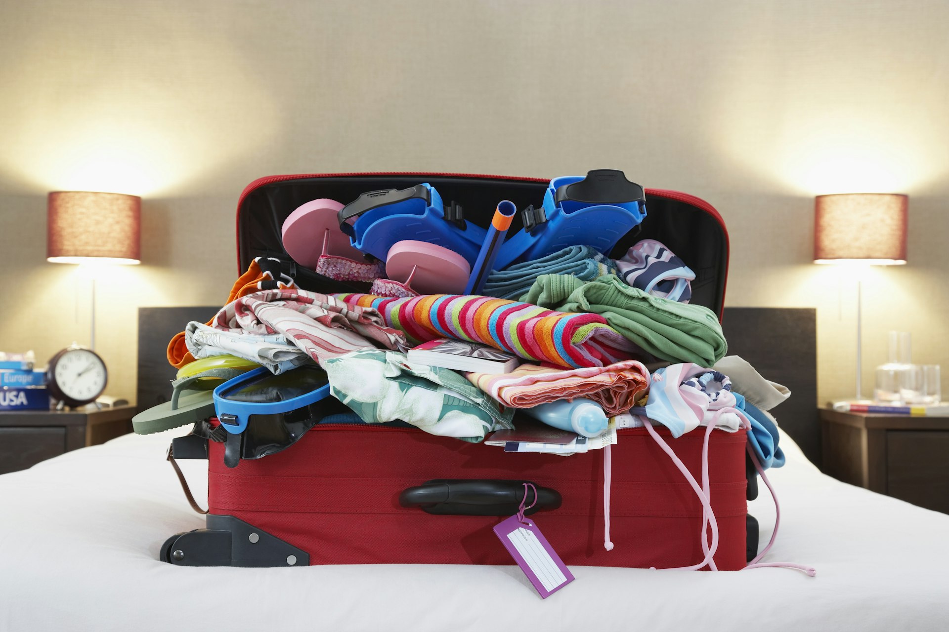 Suitcase on a bed overflowing with items 