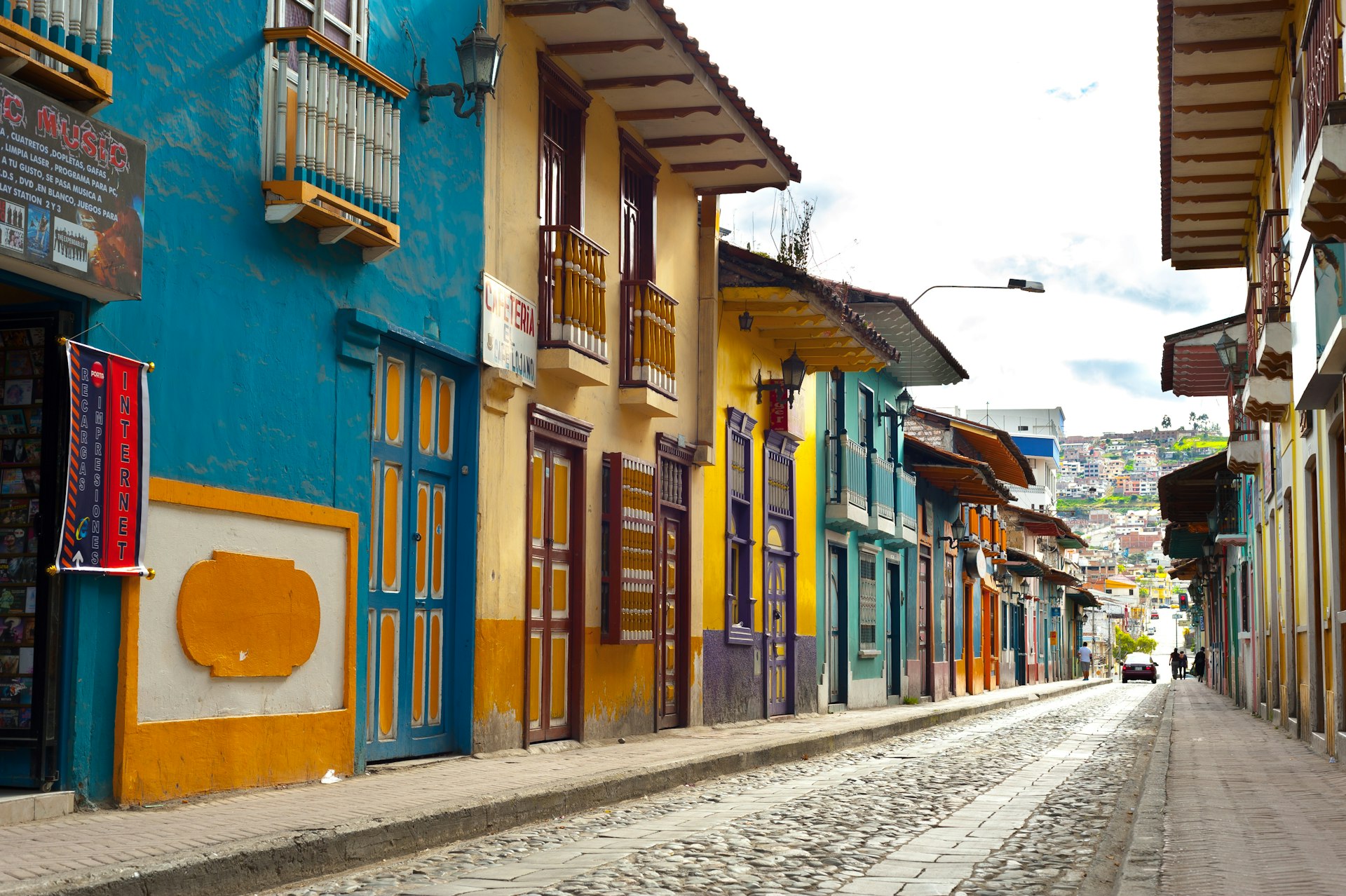 Uma fileira de casas coloridas e vitrines em uma rua de paralelepípedos