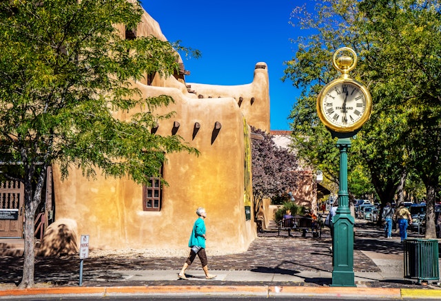A woman walks in front of a rustic building in Santa Fe, New Mexico.