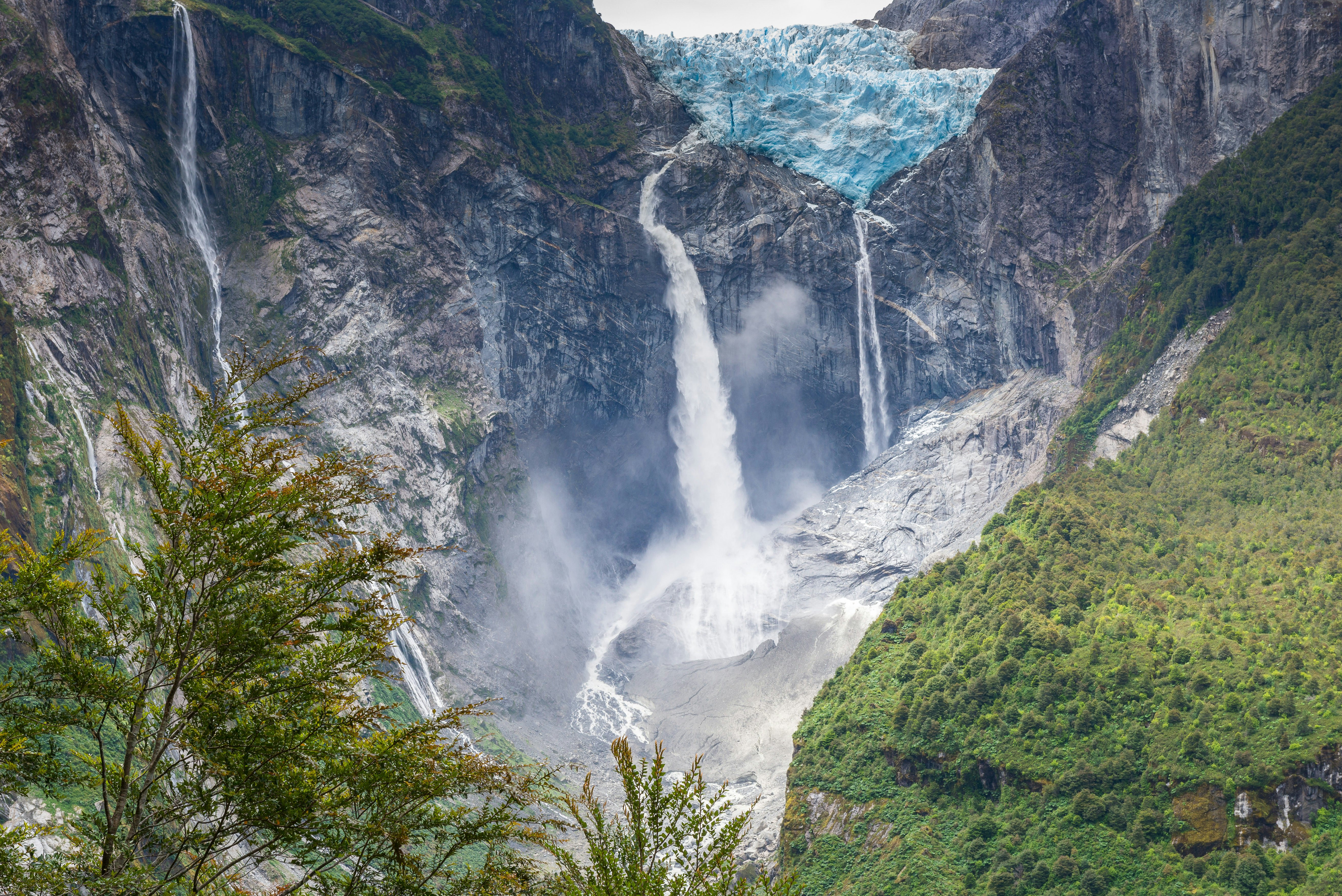 A glacier atop a rockface with a waterfall cascading down