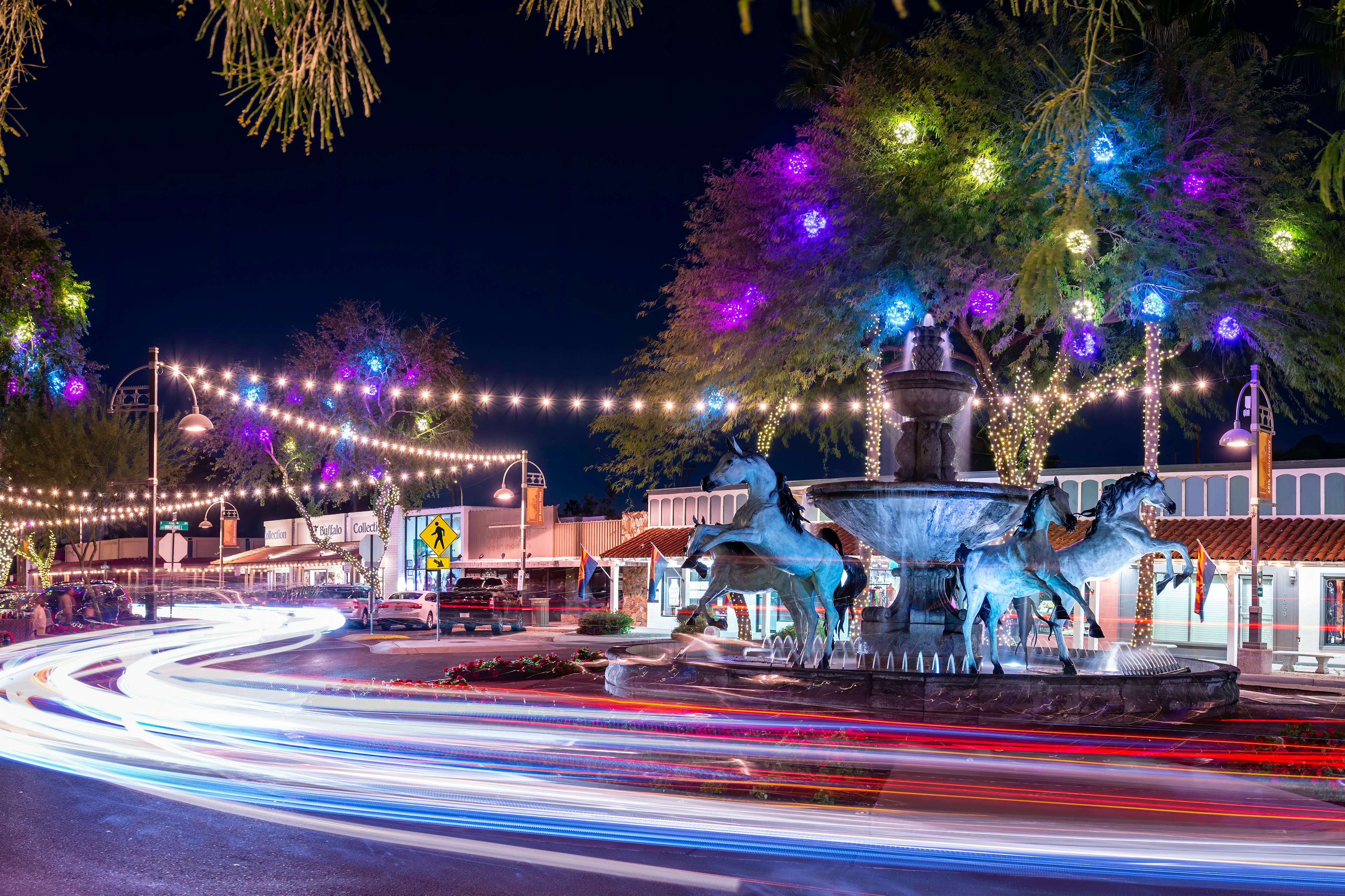 Traffic at night around Bob Parks' Bronze Horse Fountain in Old Town Scottsdale's 5th Avenue Shopping district