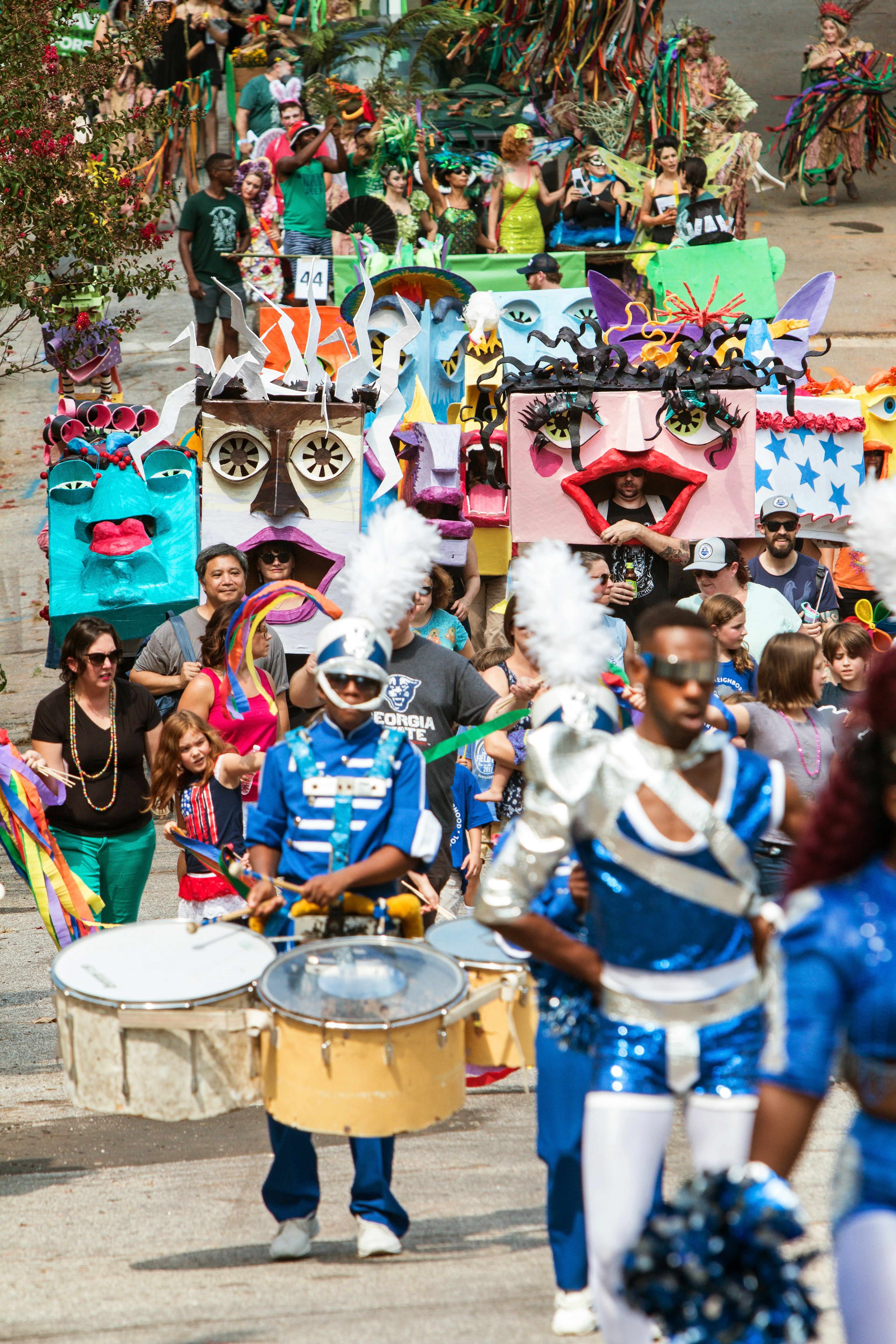 A large crowd of people are wearing masks and costumes as they parade in the East Atlanta Strut festival