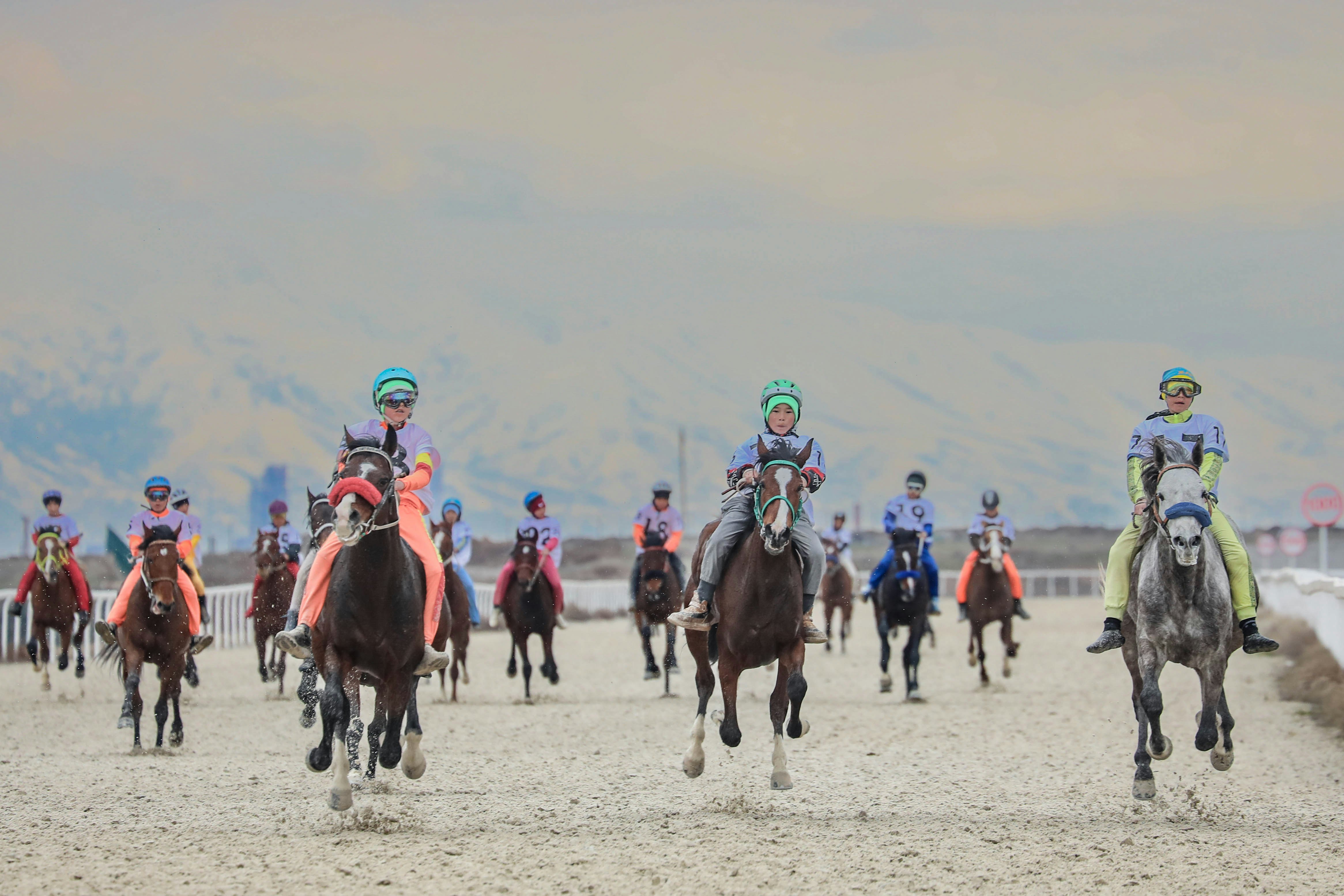 Horseback riders in a race on a sandy course