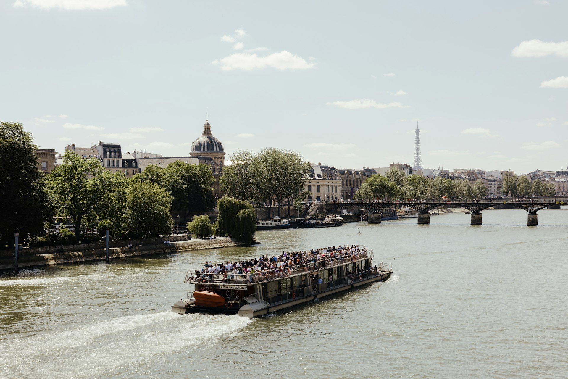 VIew of a riverboat in the Seine with the Dome of Institut de France and the Eiffel Tower in the background, Paris, France.