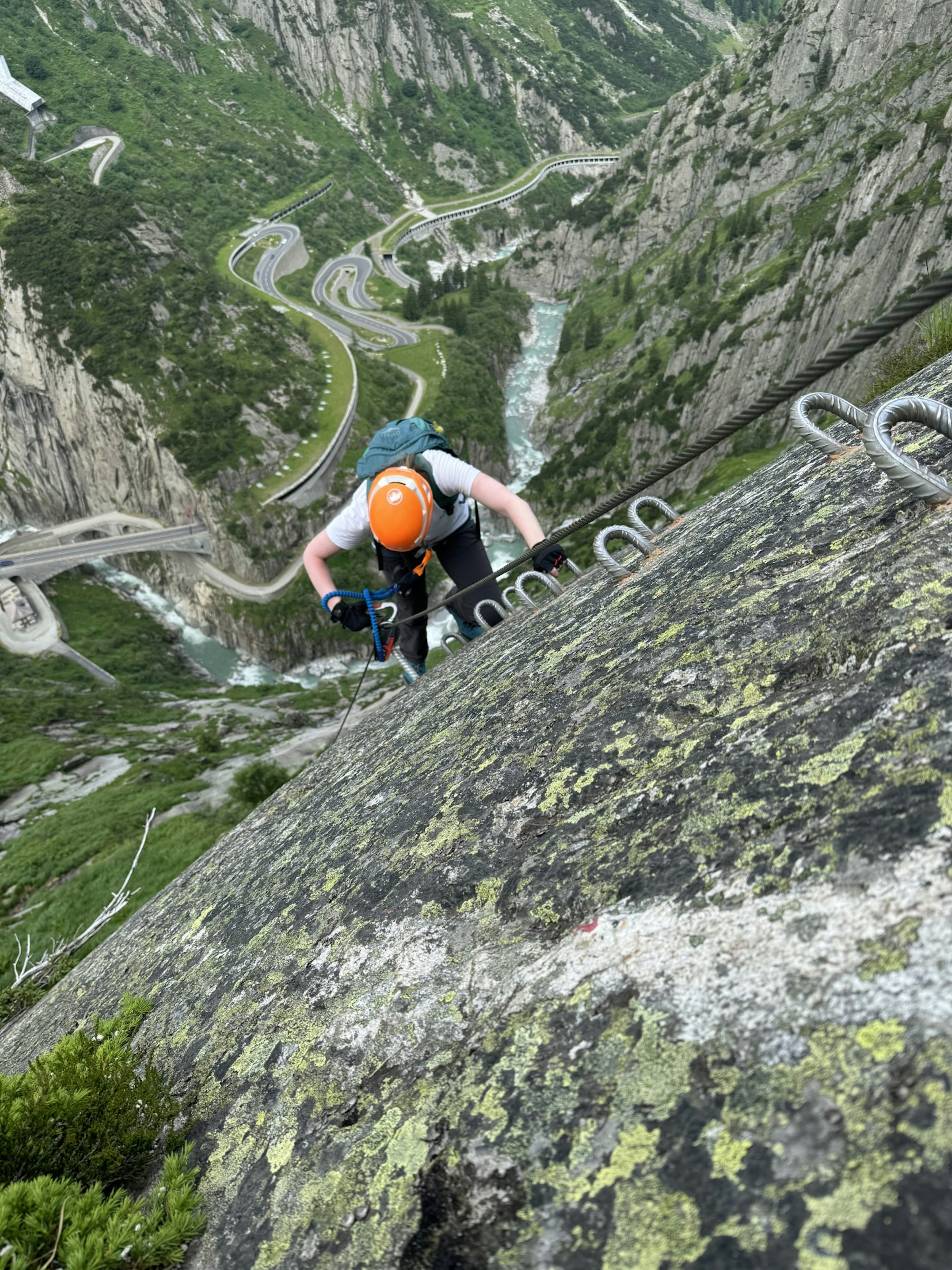 A climber climbs a sheer cliff using cables and rungs