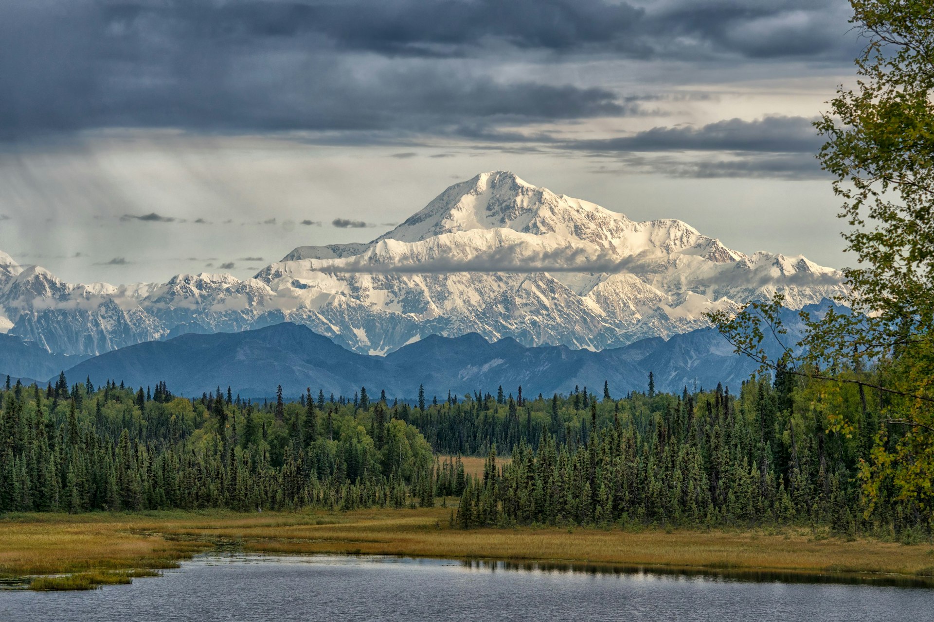 A vast snow-topped mountain towers over a landscape