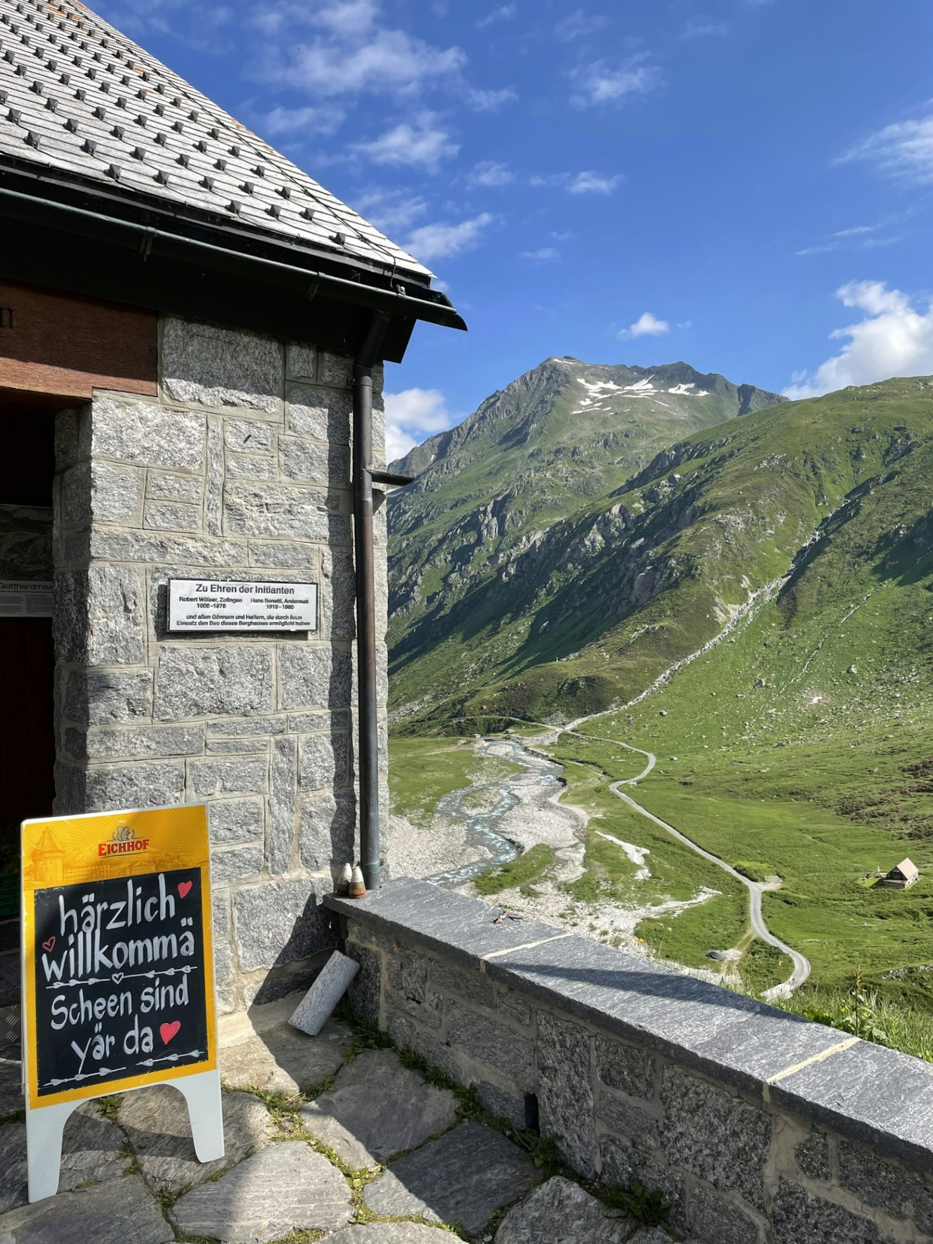 The entrance to a stone mountain hut with rolling hills and mountains stretching into the distance