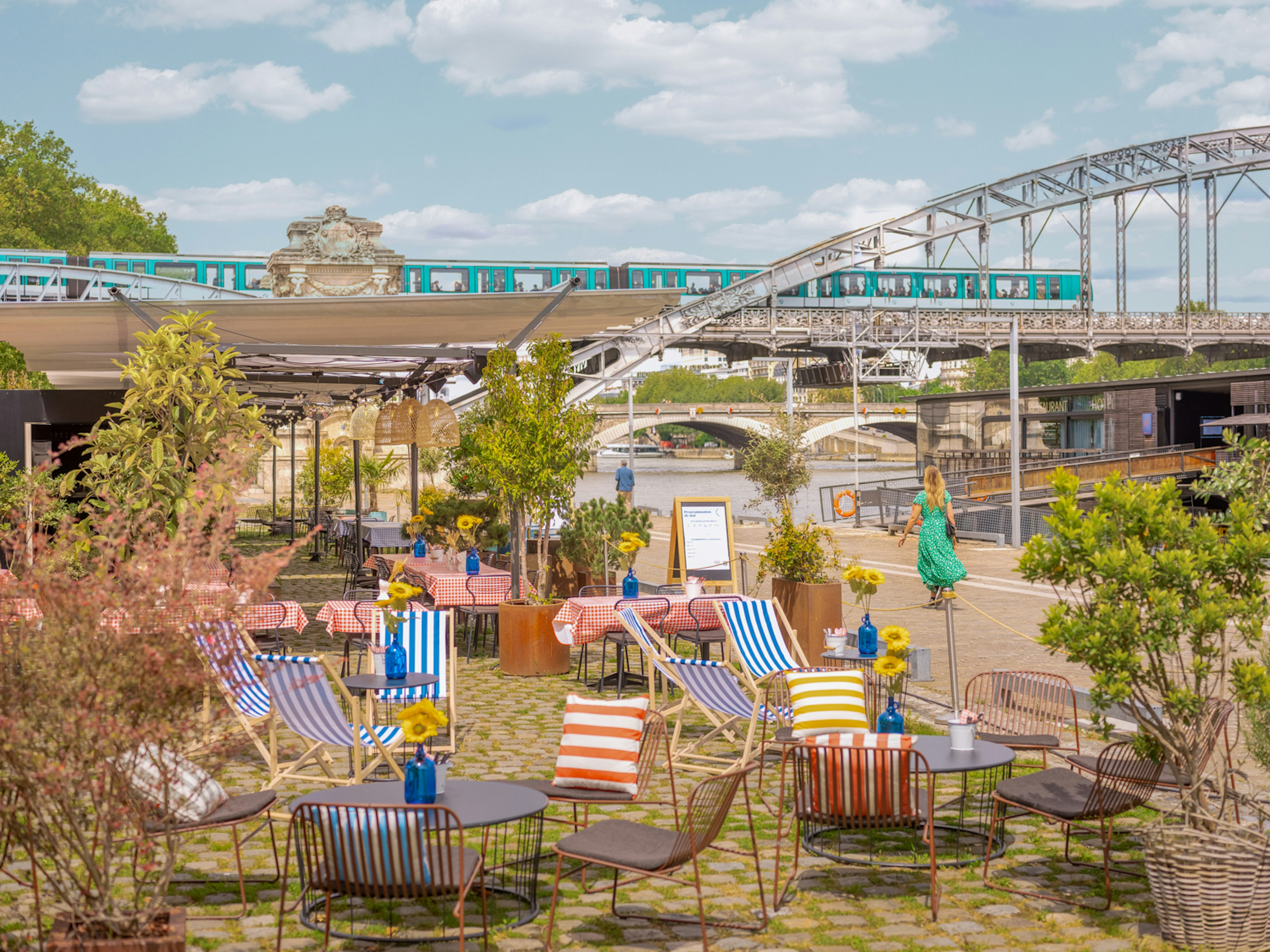 A terrace bar beside a river with many striped deckchairs