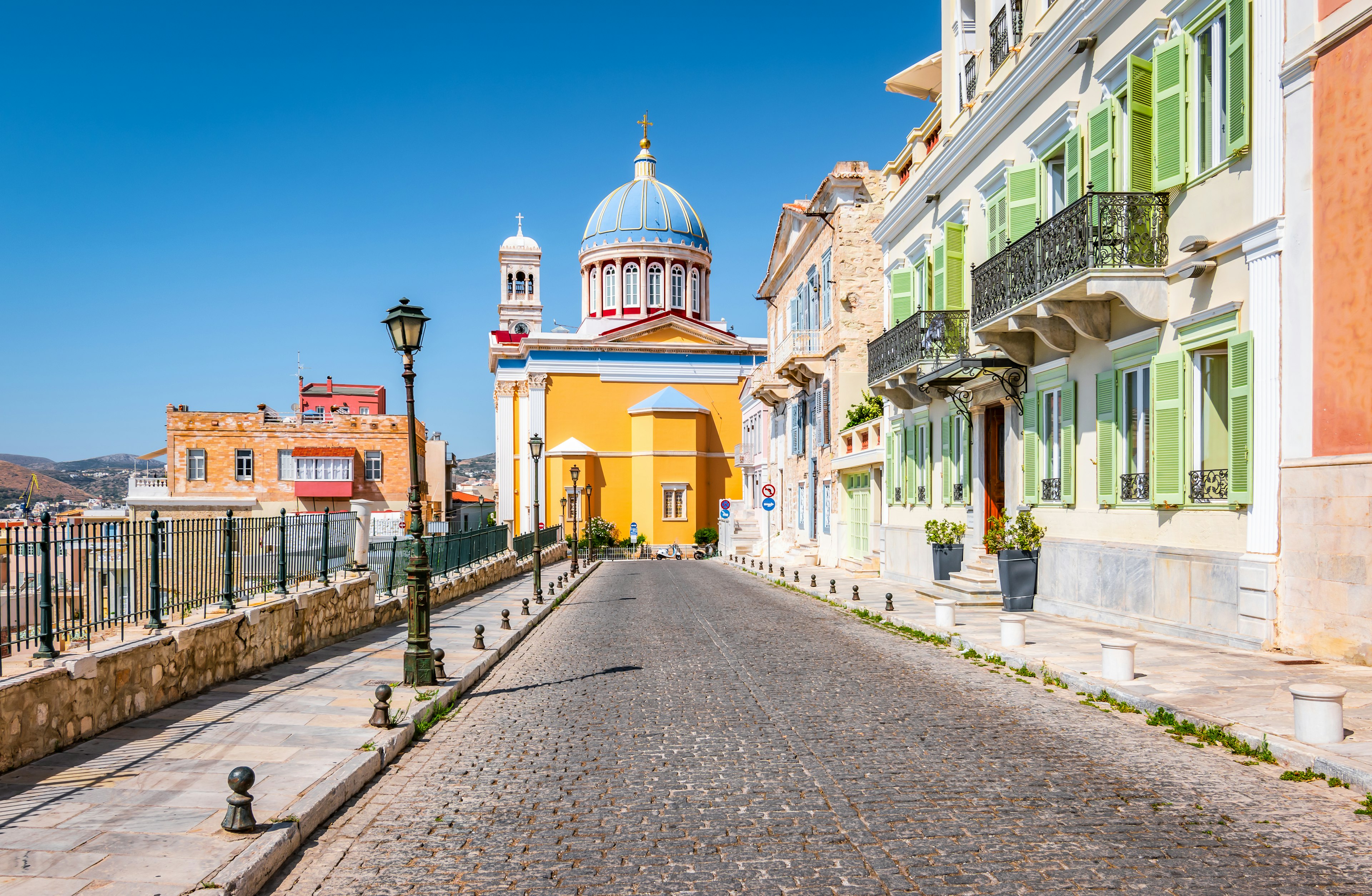 Colorful image with cobblestone street, colored buildings and lanterns in town center of Ermoupoli, Syros, Greek Islands.